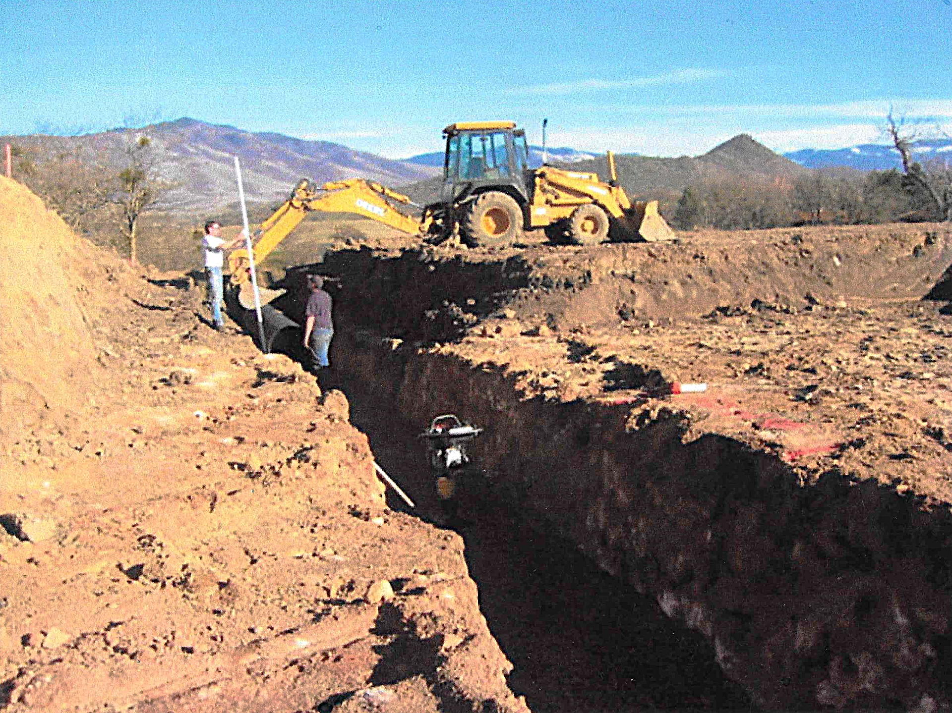 Backhoe digging trench for a gravity-fed water pipeline in Ashland, Oregon.