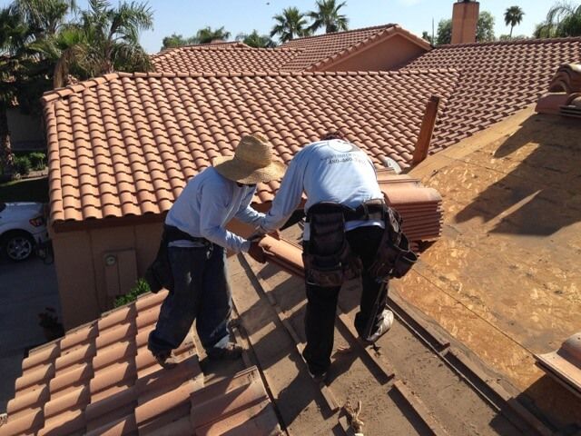 Two men are working on the roof of a house