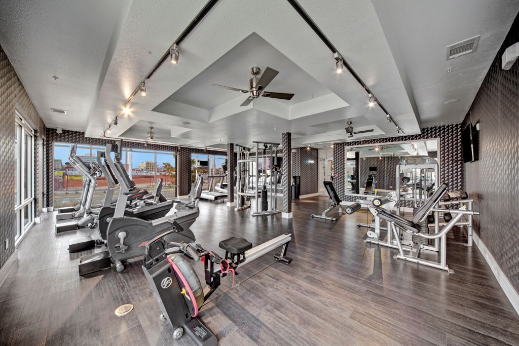 A large gym with a lot of equipment and a ceiling fan.