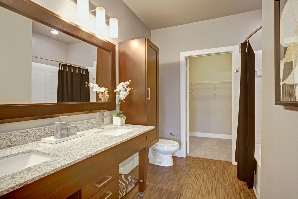 A bathroom with two sinks , a toilet , and a mirror.