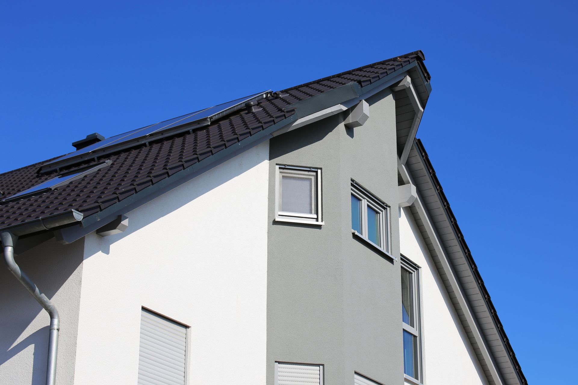 A white house with a black roof and a blue sky in the background.