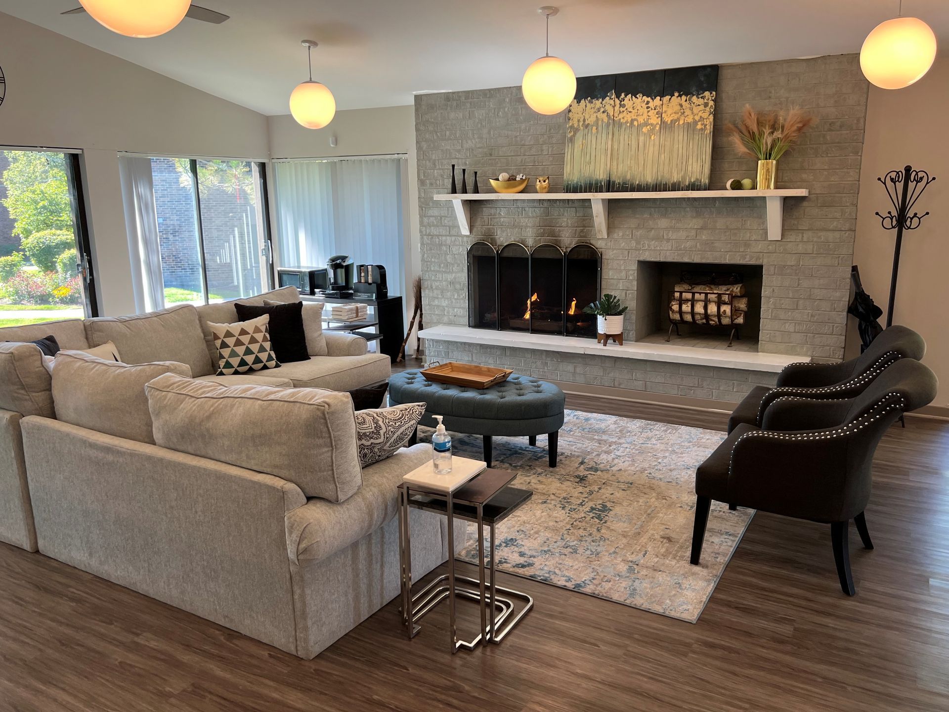 Living room with gray sectional, fireplace, and round pendant lights.