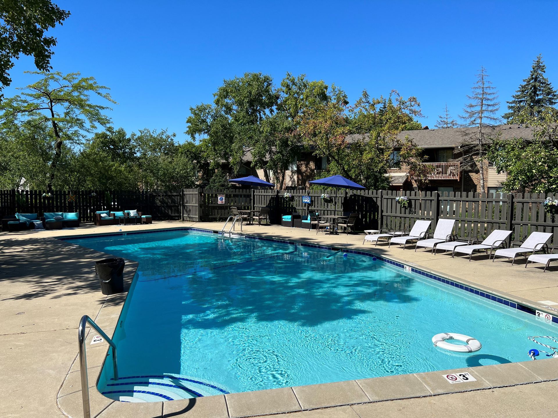 Swimming pool surrounded by lounge chairs and shade umbrellas on a sunny day.
