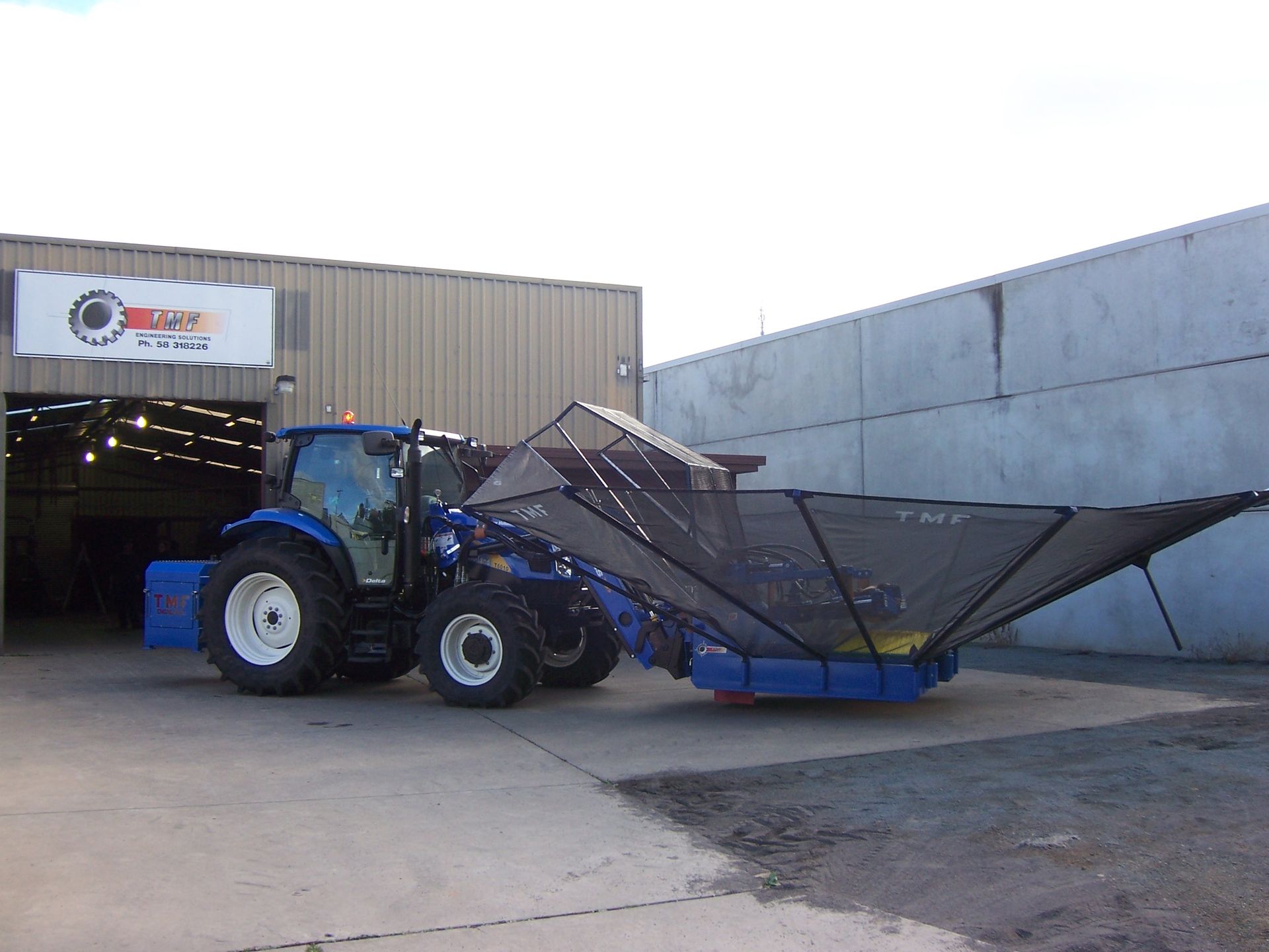 A blue tractor is parked in front of a building — TMF Engineering In Benalla, VIC