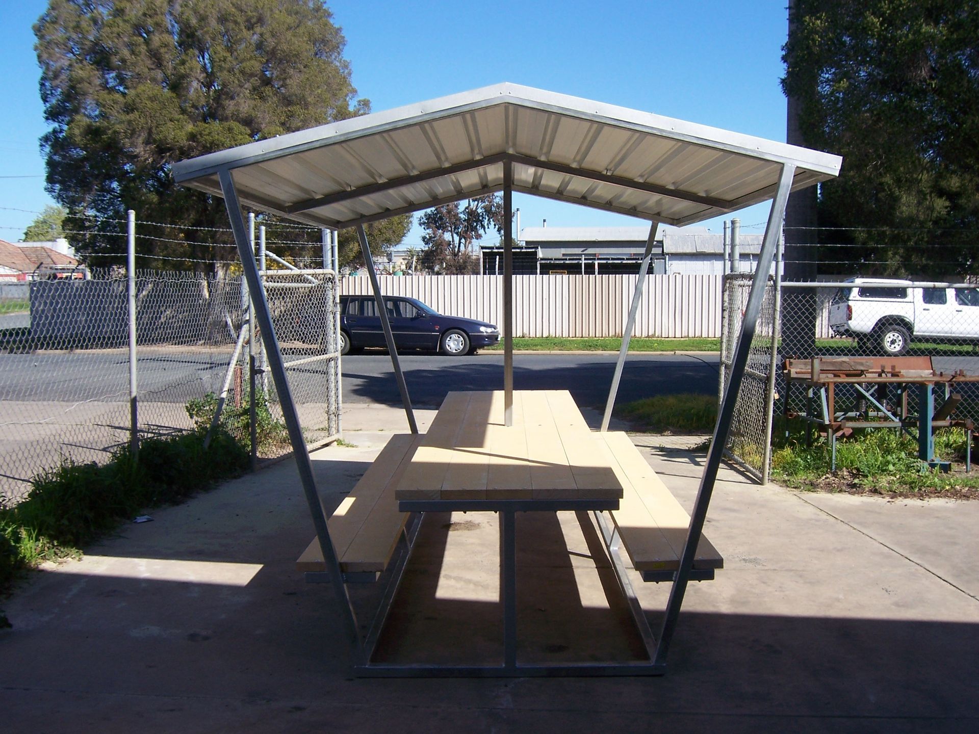 A picnic table under a white roof in a parking lot — TMF Engineering In Benalla, VIC