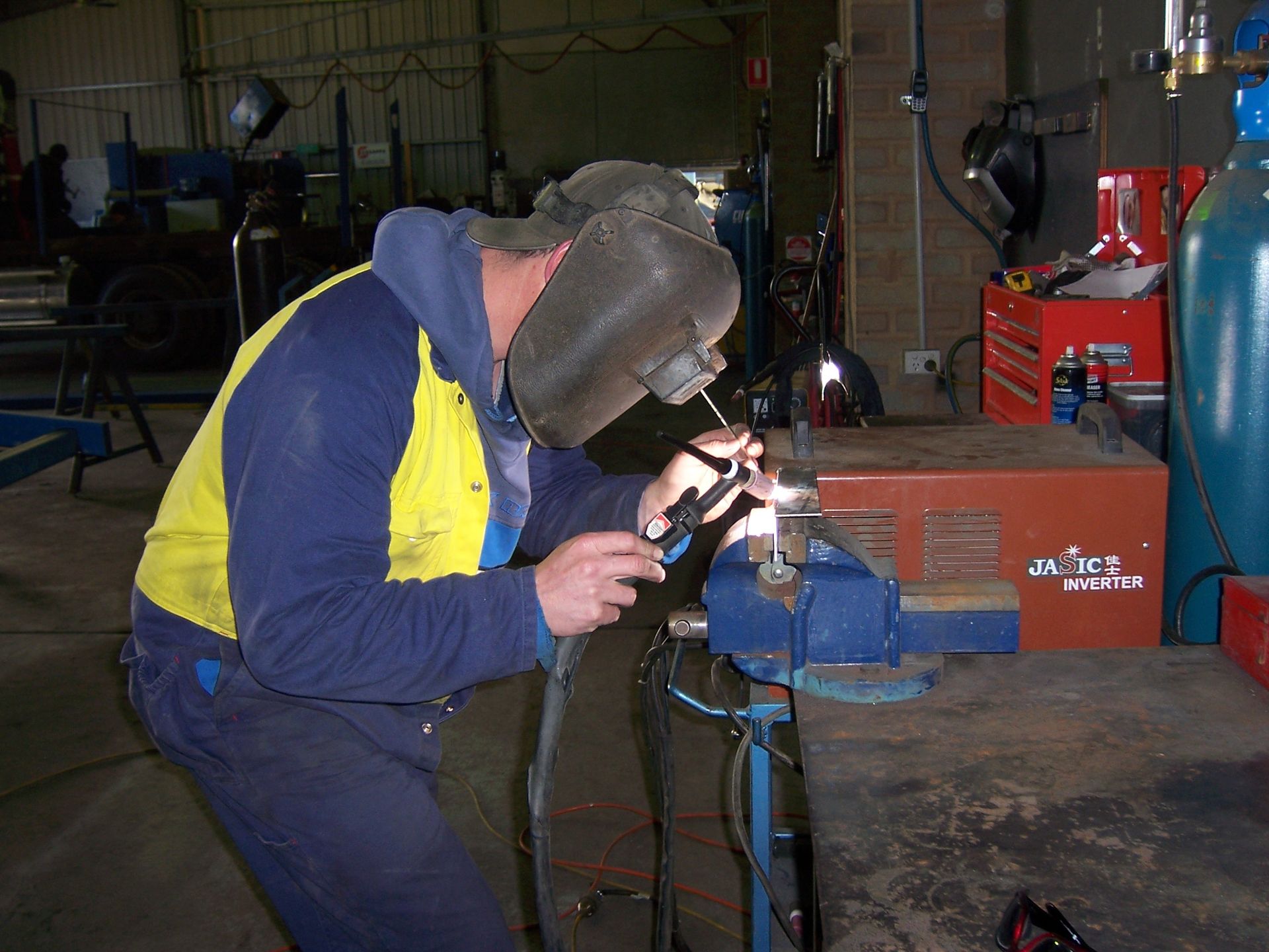 A man wearing a welding helmet is working on a piece of metal — TMF Engineering In Benalla, VIC