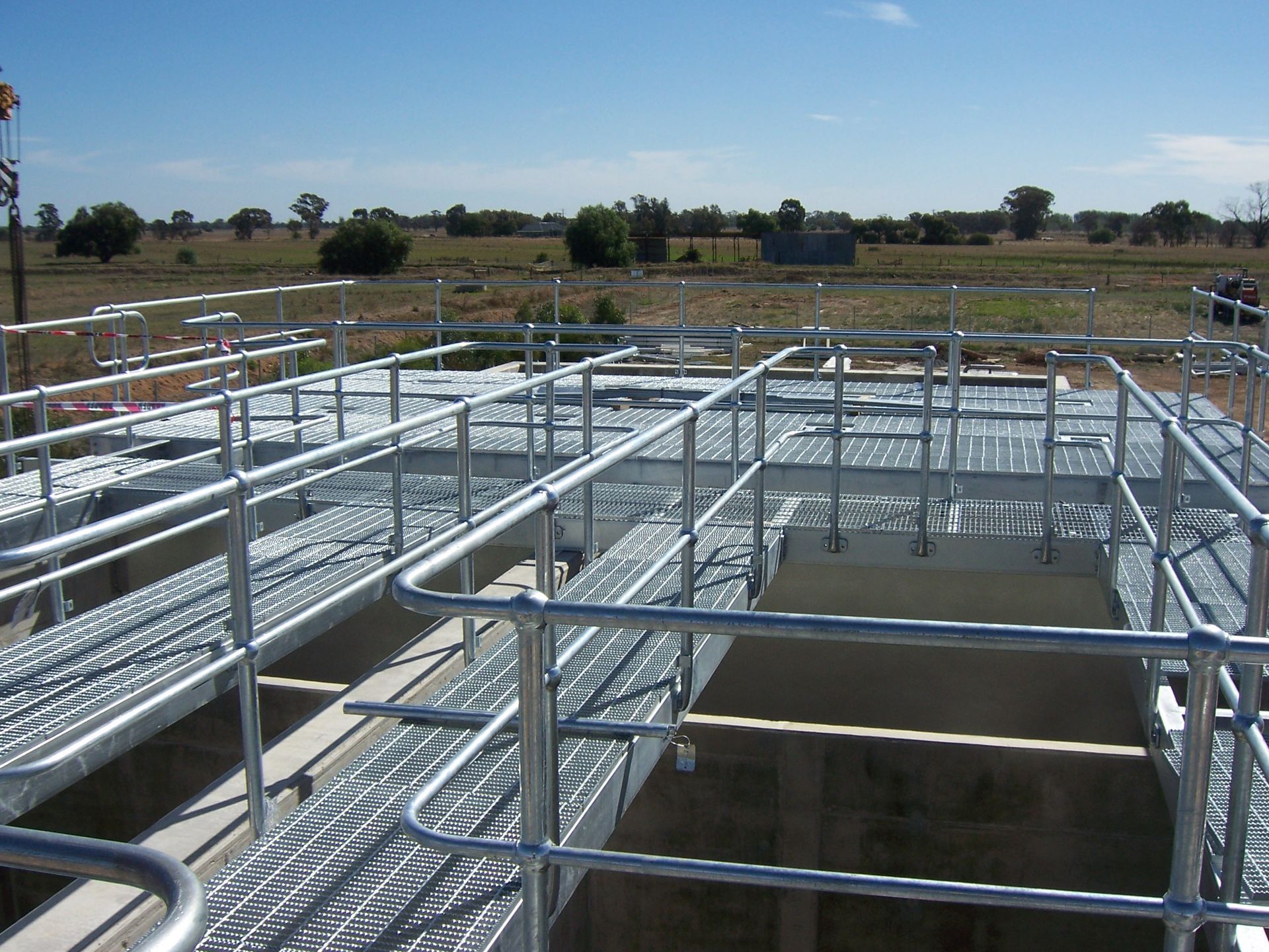 A metal fence surrounds a concrete structure with a blue sky in the background — TMF Engineering In Benalla, VIC