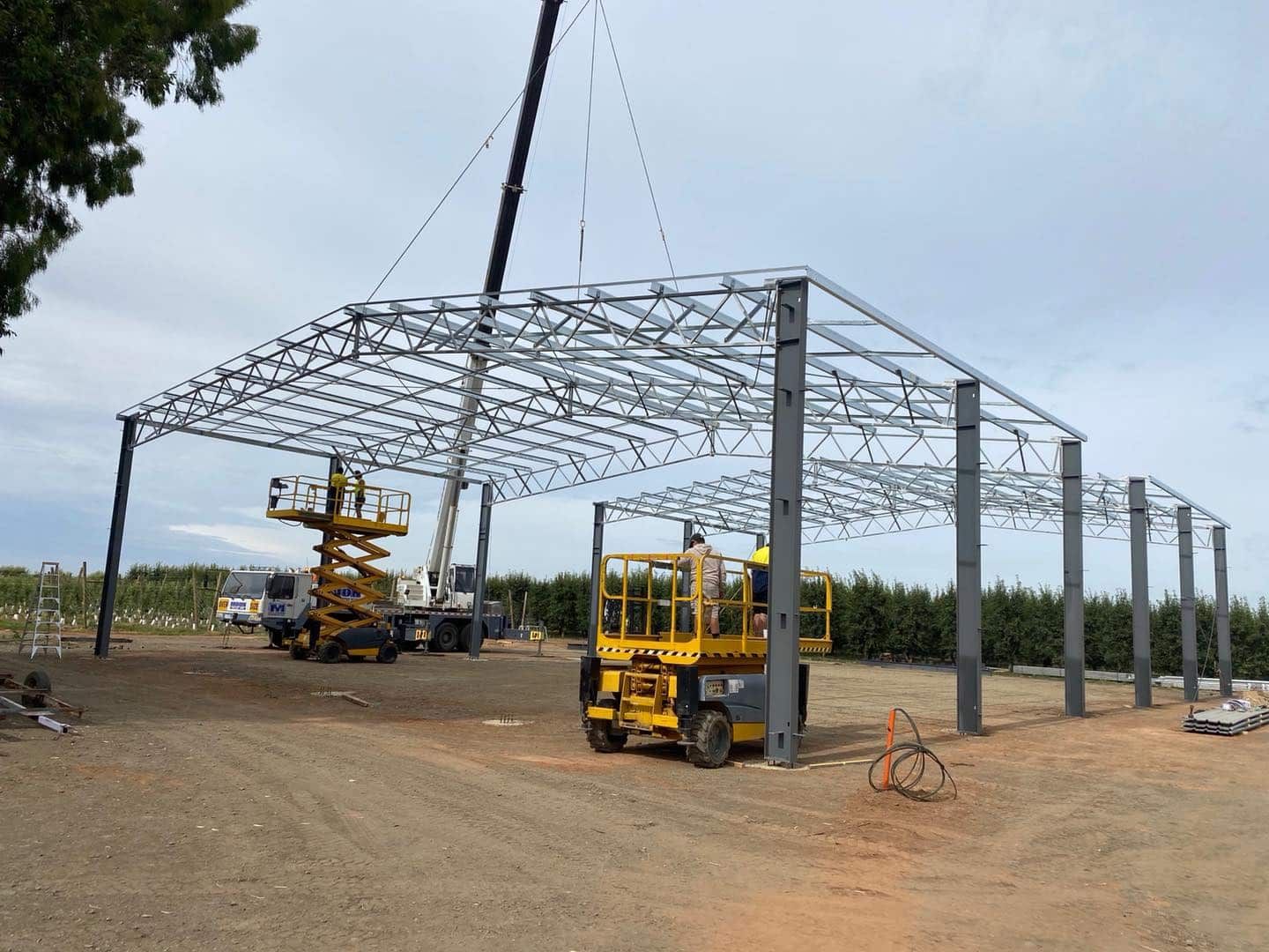 A Crane Is Lifting A Metal Structure In A Dirt Field — TMF Engineering In Cobram, VIC
