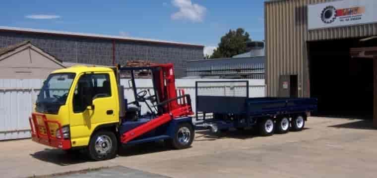 A Yellow Truck With A Forklift Attached To It Is Parked In Front Of A Building — TMF Engineering In Numurkah, VIC