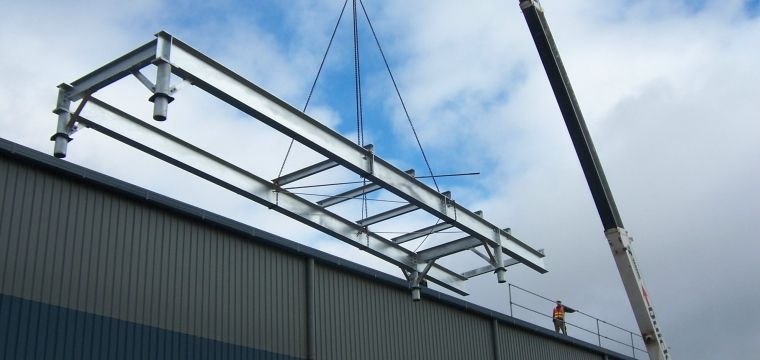 A crane is lifting a metal structure on top of a building — TMF Engineering In Benalla, VIC