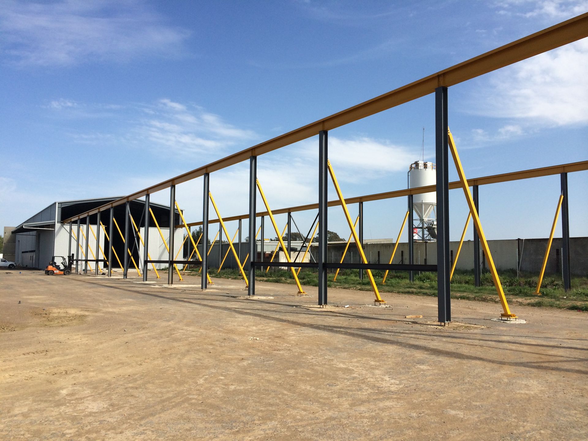 A large metal structure is being built in a dirt field — TMF Engineering In Benalla, VIC