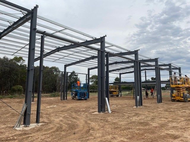 A large metal structure is being built in a dirt field — TMF Engineering In Benalla, VIC