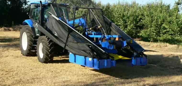A Blue Tractor Is Driving Through A Field With Trees In The Background — TMF Engineering In Seymour, VIC