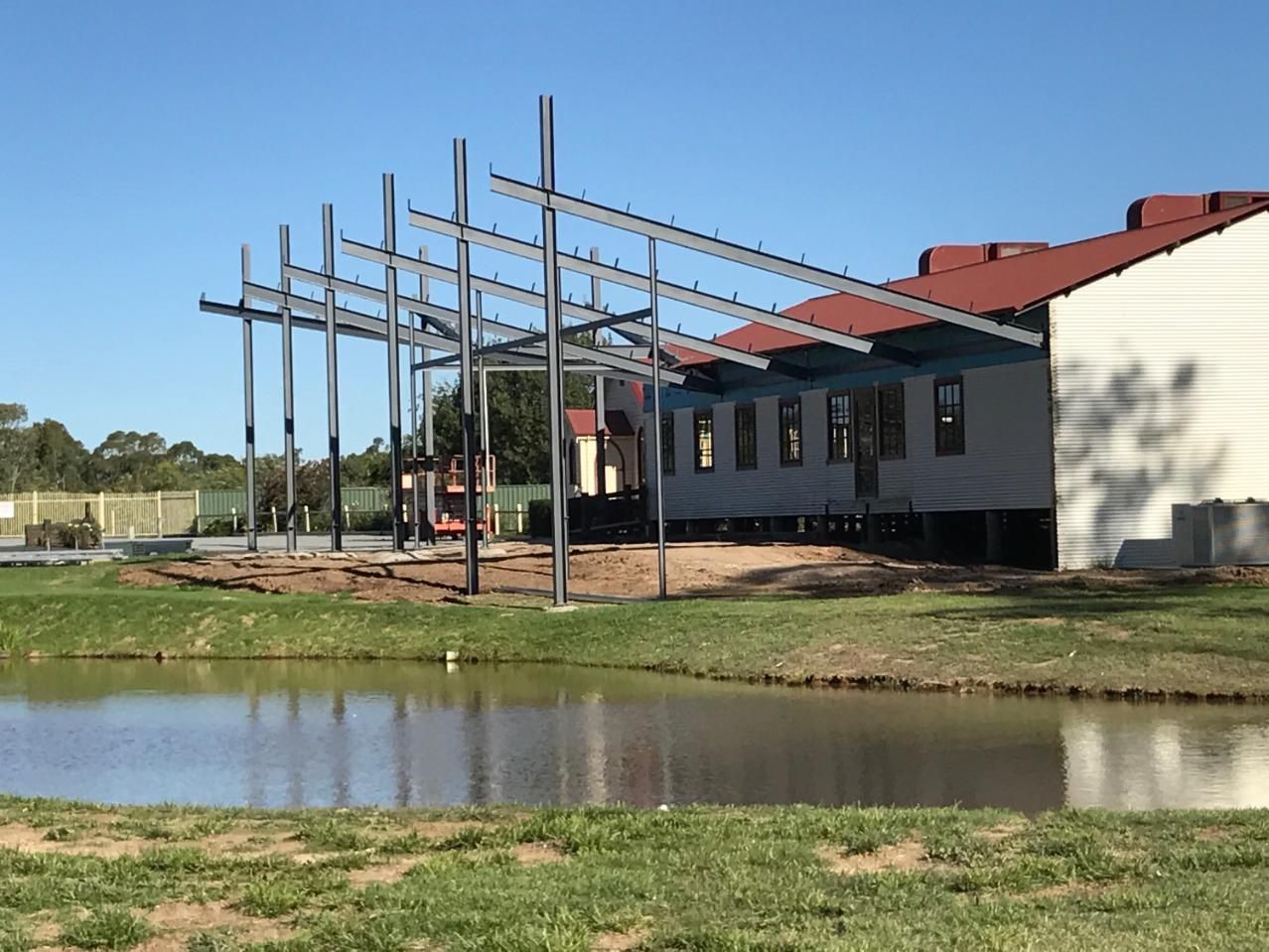A Building Under Construction With A Pond In Front Of It — TMF Engineering In Shepparton, VIC