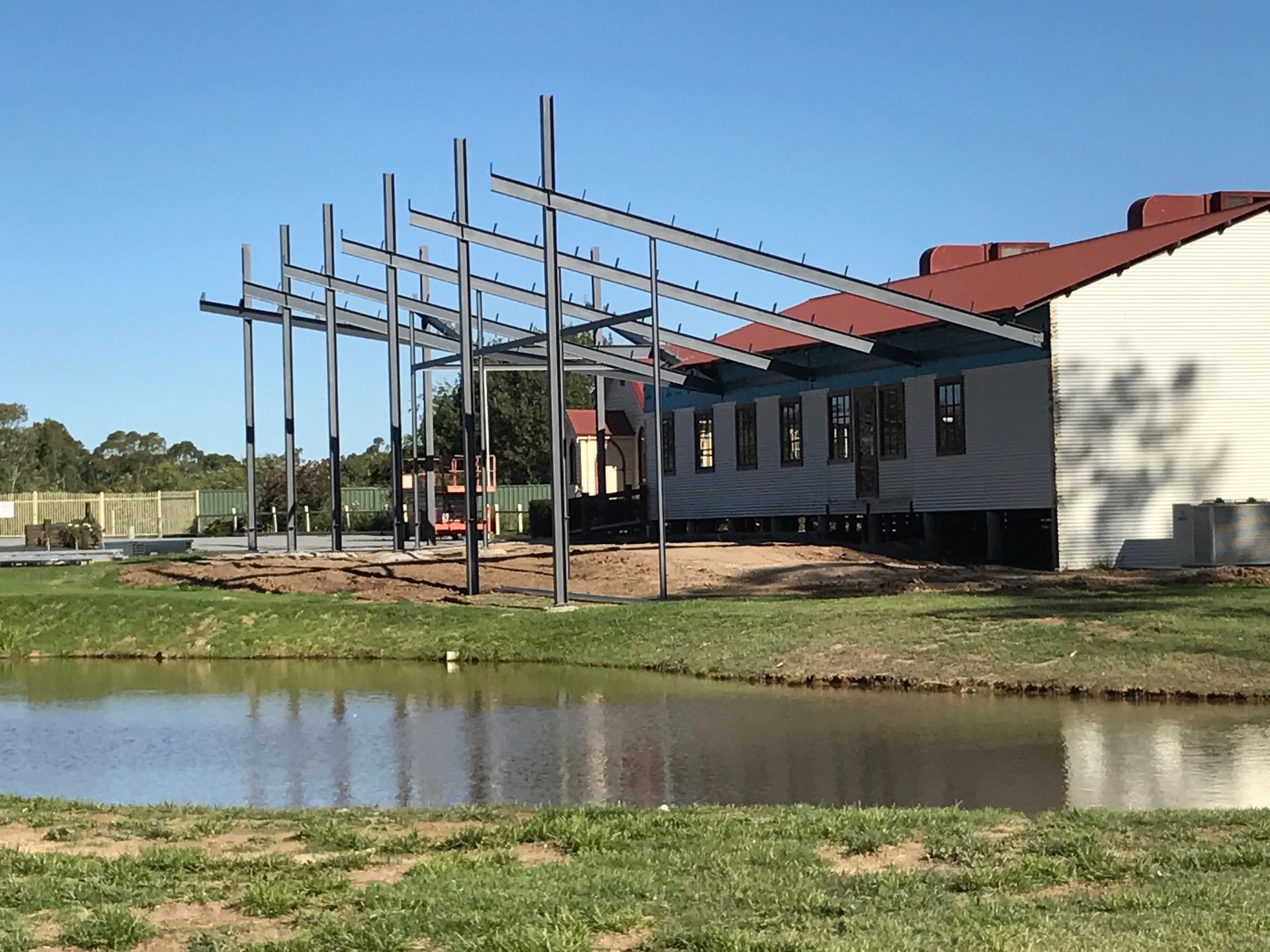 A building under construction with a pond in front of it — TMF Engineering In Benalla, VIC