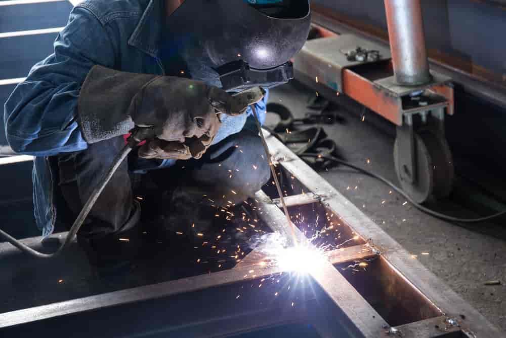 A Man Is Welding A Piece Of Metal In A Factory — TMF Engineering In Seymour, VIC
