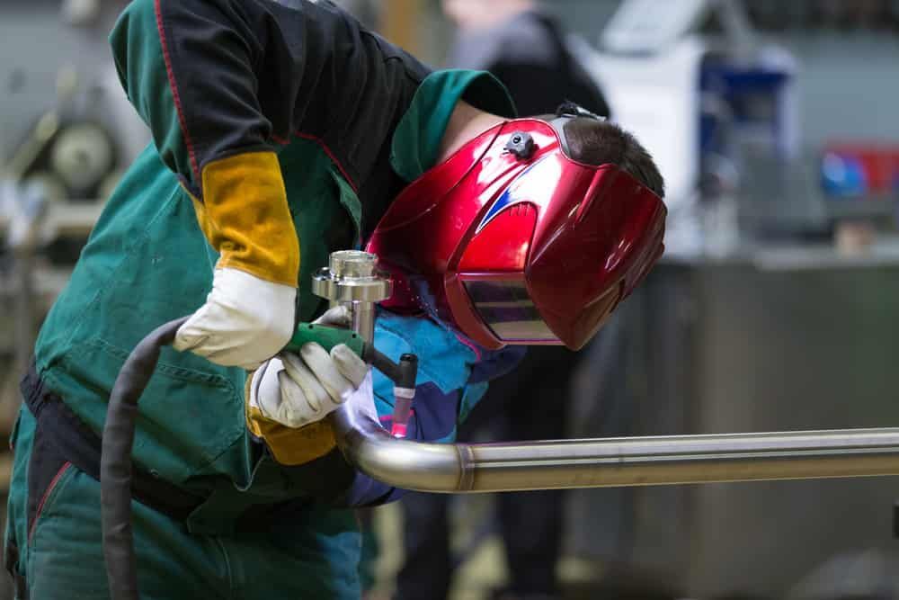 A Man Wearing A Welding Helmet Is Welding A Pipe In A Factory — TMF Engineering In Seymour, VIC