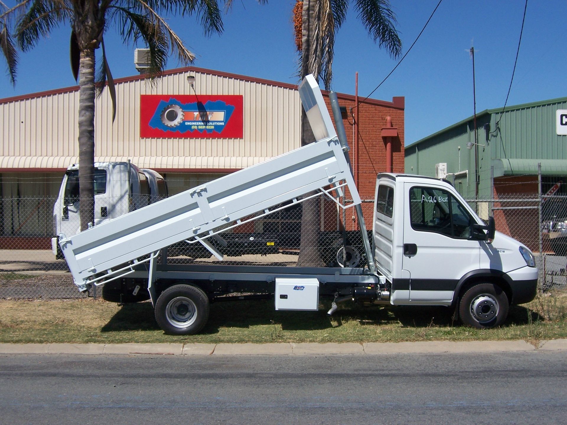 A White Truck With Its Tray Lifted Up Is Parked On The Side Of The Road — TMF Engineering In Shepparton, VIC