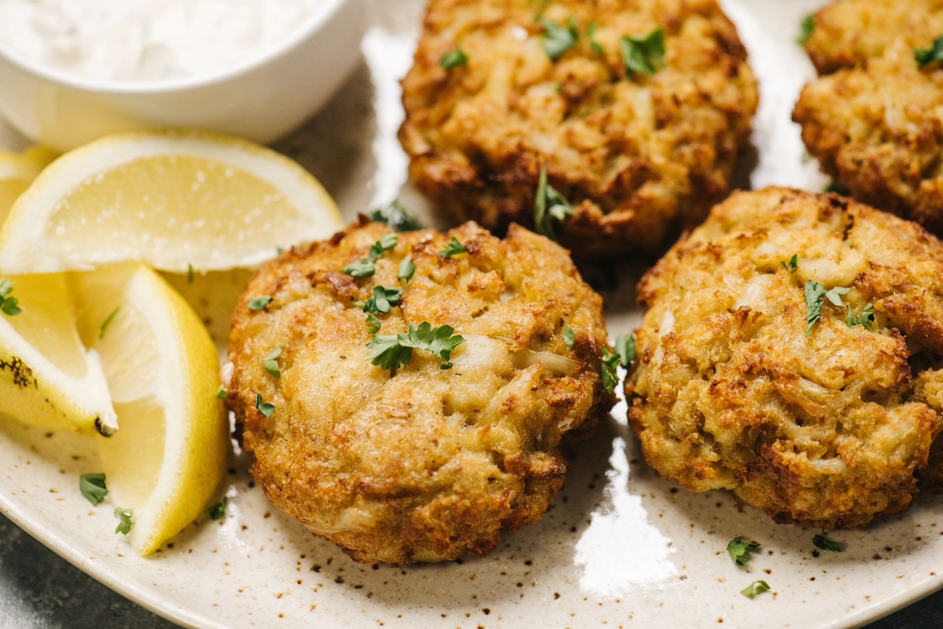 A white plate topped with crab cakes and lemon slices.