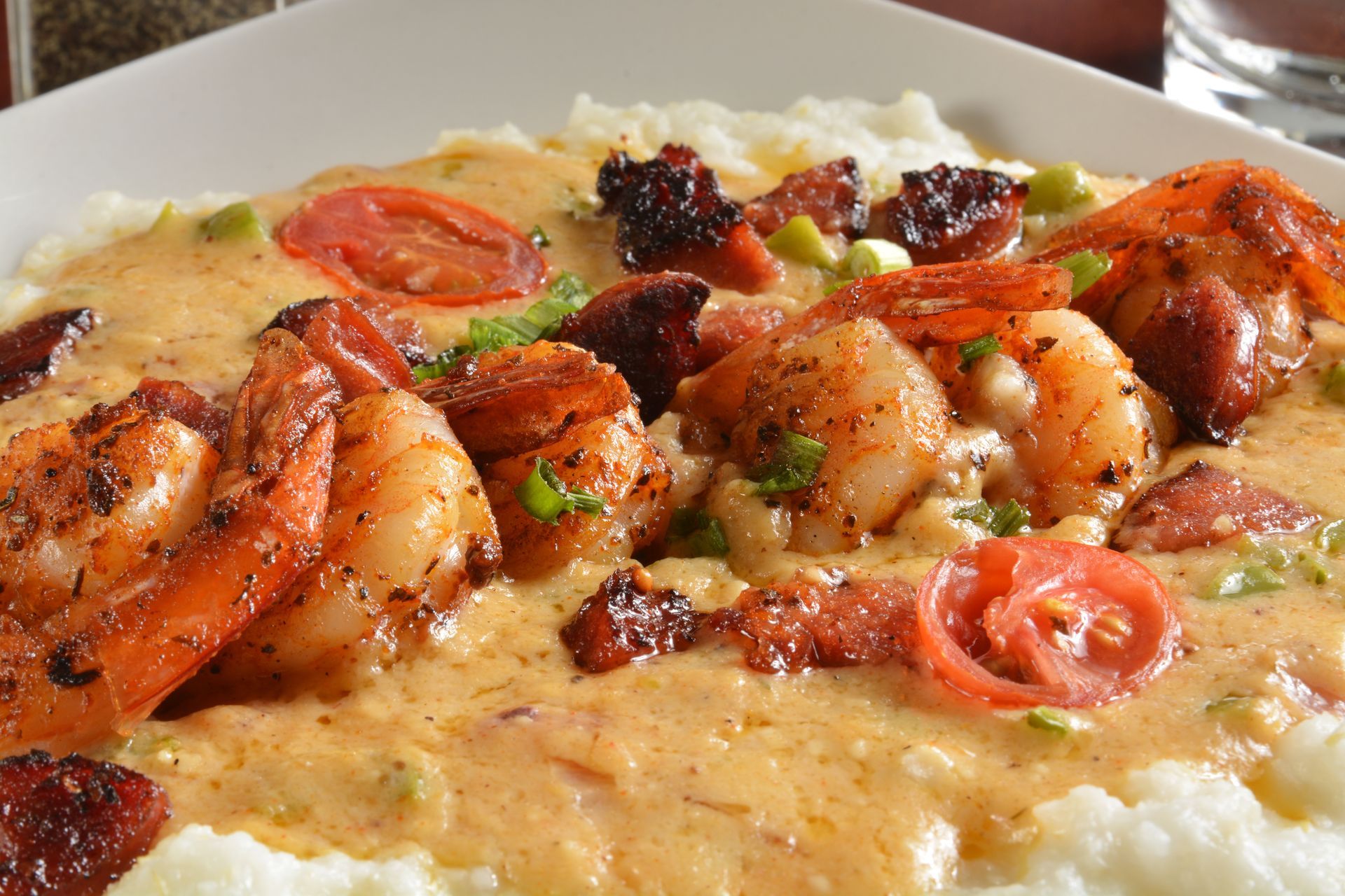A close up of a plate of shrimp and grits on a table.