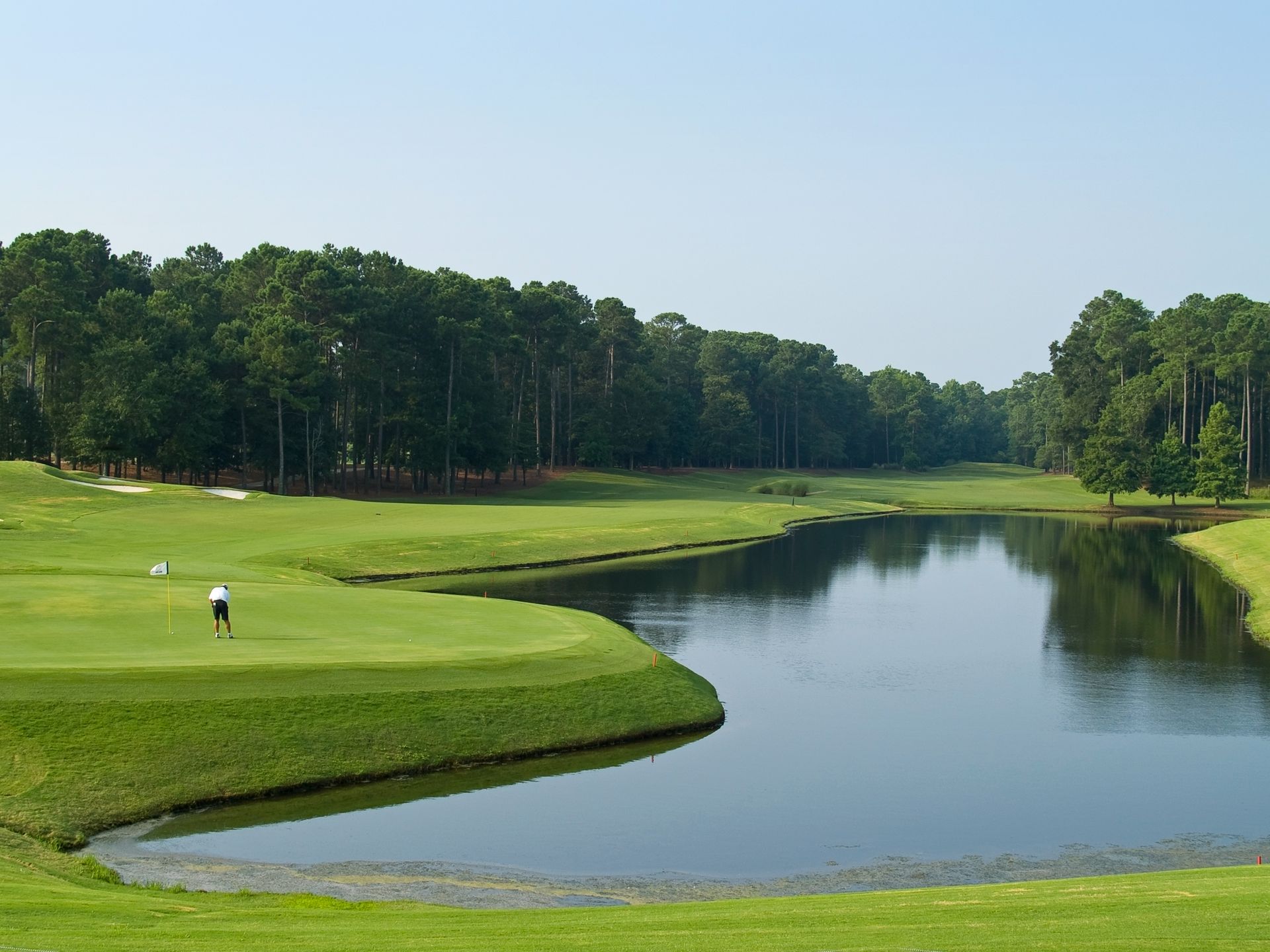 A man is playing golf on a golf course next to a lake.