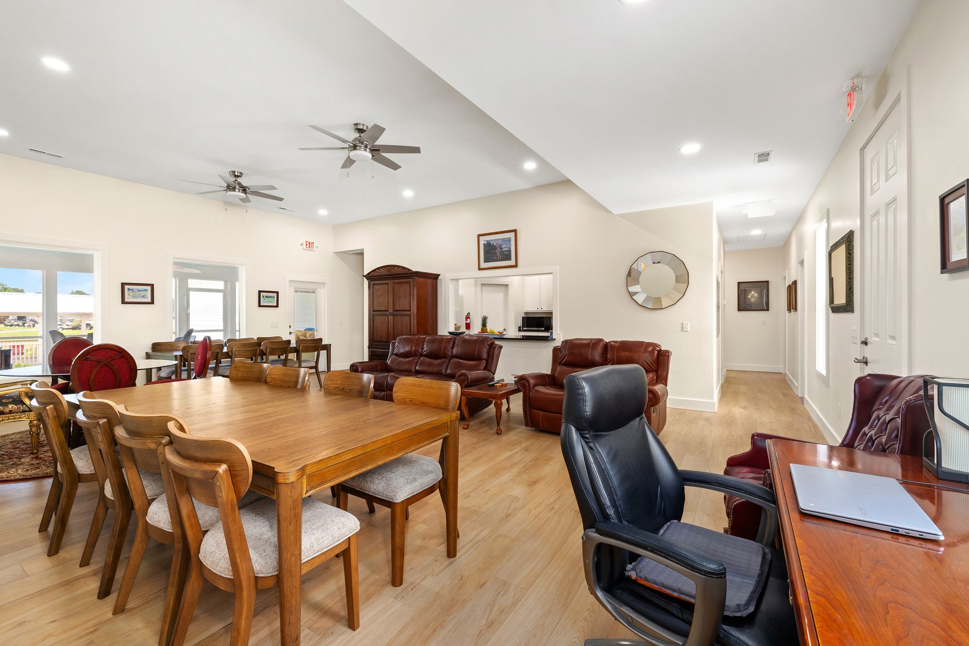 Spacious room with a large wooden table, chairs, seating area, desk, and hallway.