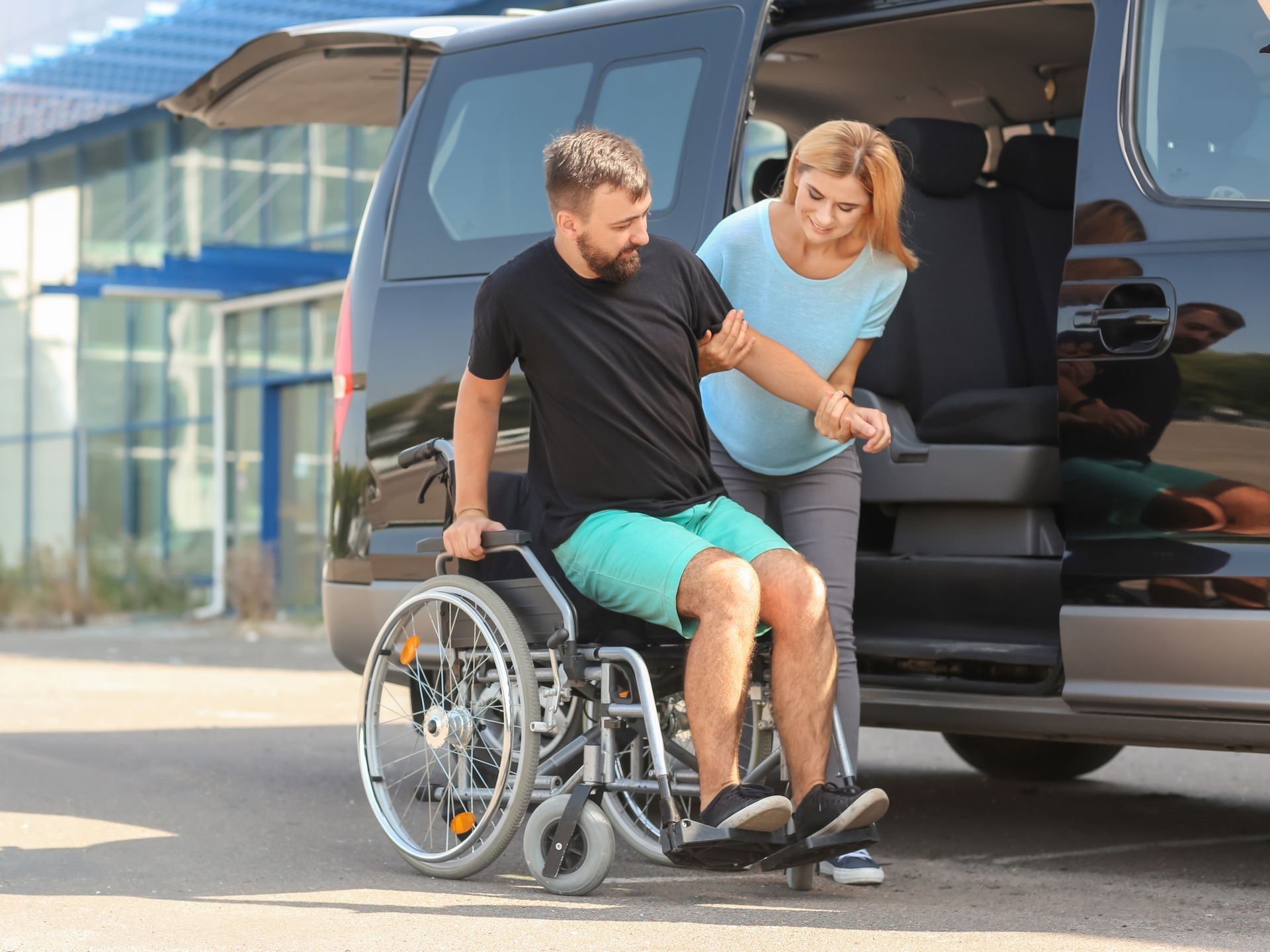 A person in a wheelchair is being assisted by another individual while boarding a wheelchair-accessible van.