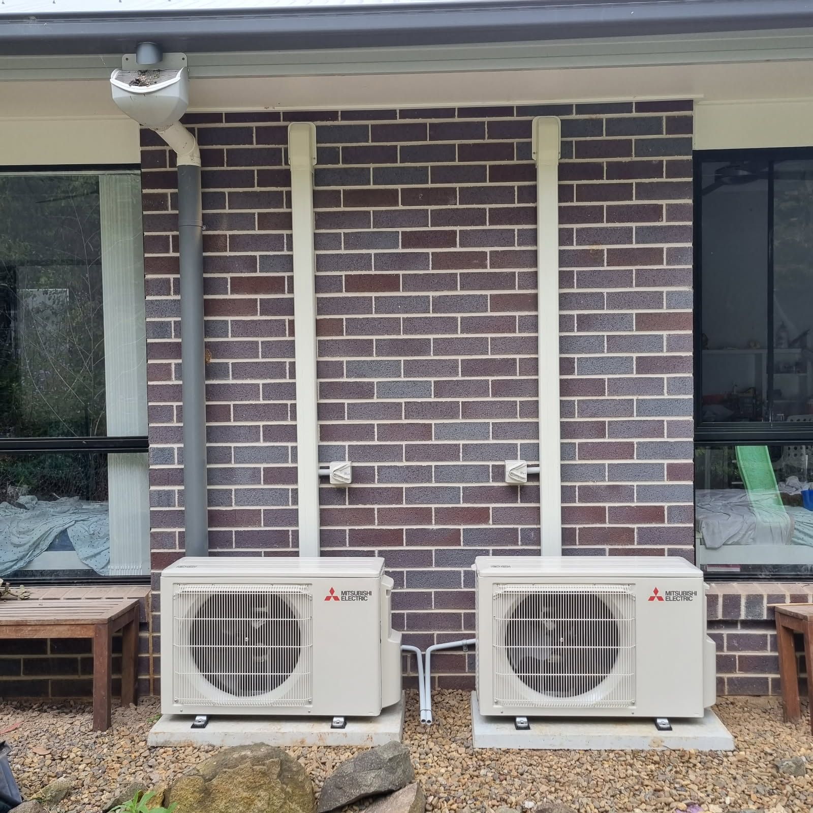 A Person Is Holding A Remote Control In Front Of An Air Conditioner — Derek Knust Electrical In Mons, QLD