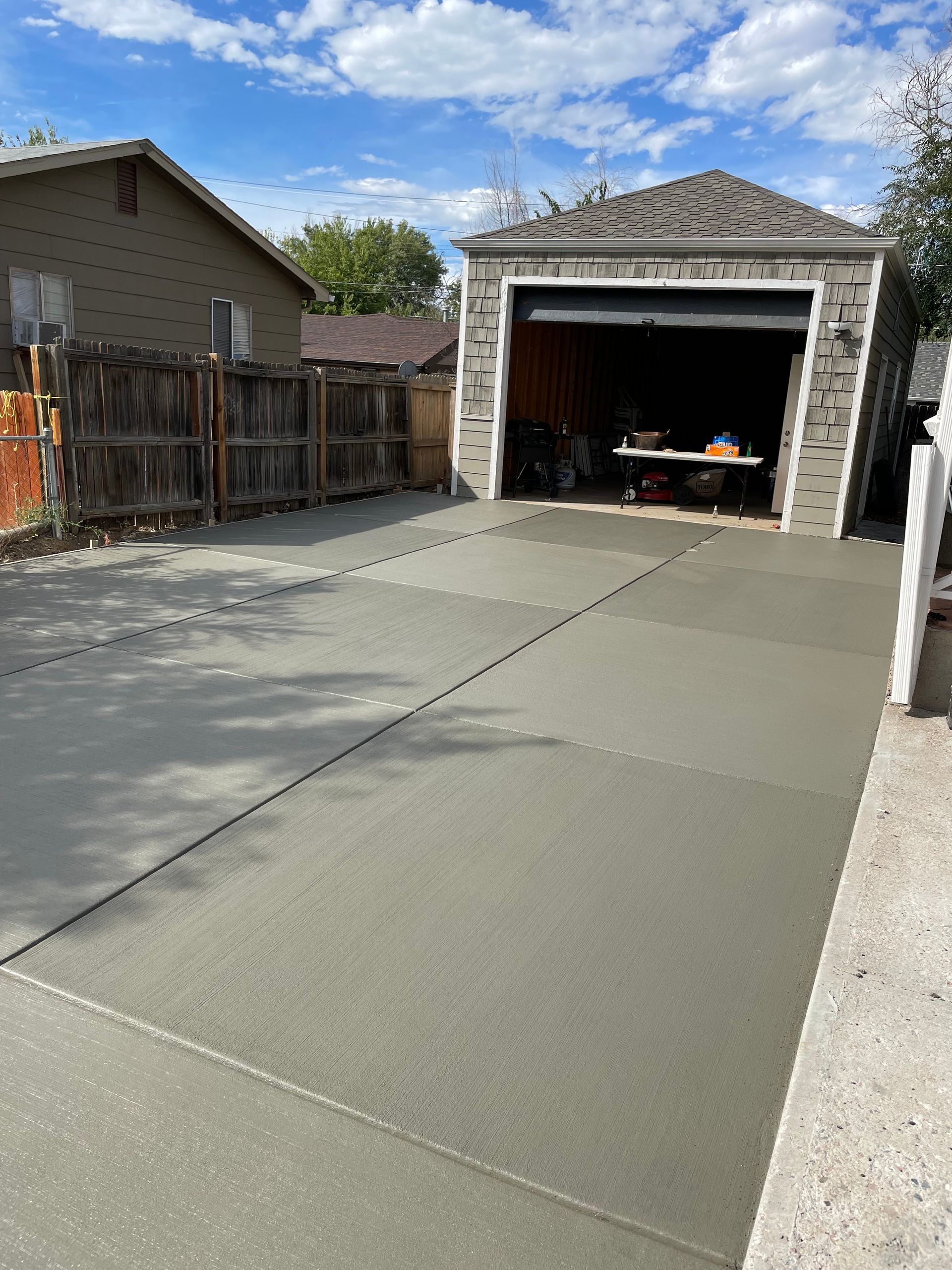 A concrete driveway leading to a garage with a table in front of it.