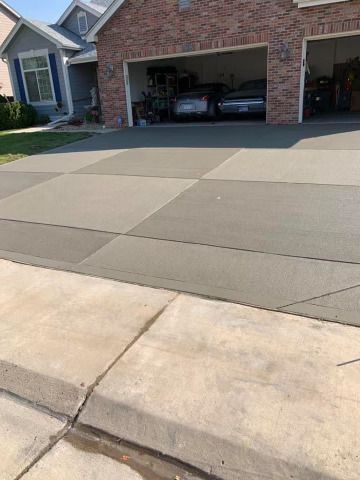 Two cars are parked in a driveway in front of a brick house.