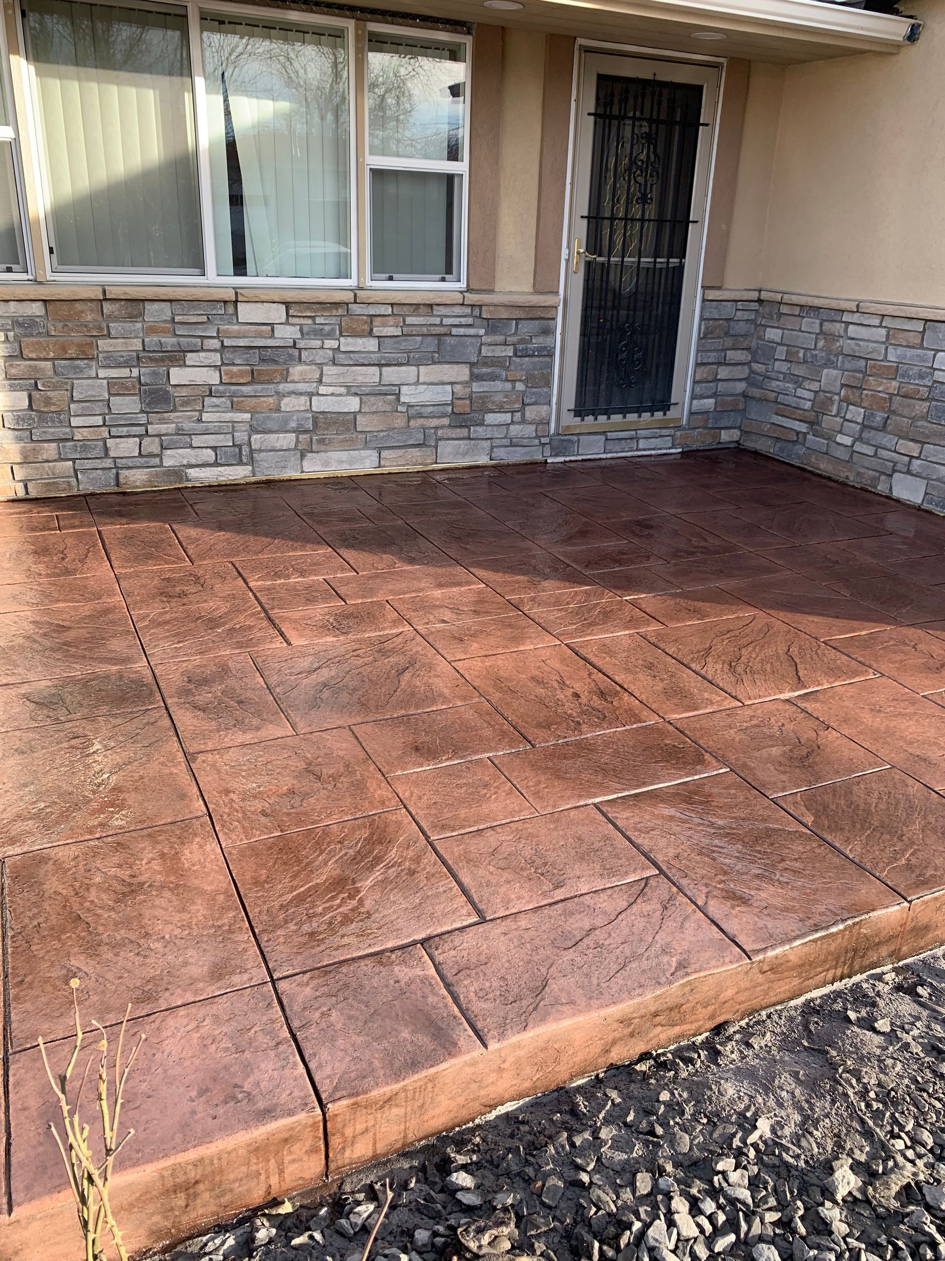 A concrete patio in front of a house with a stone wall.