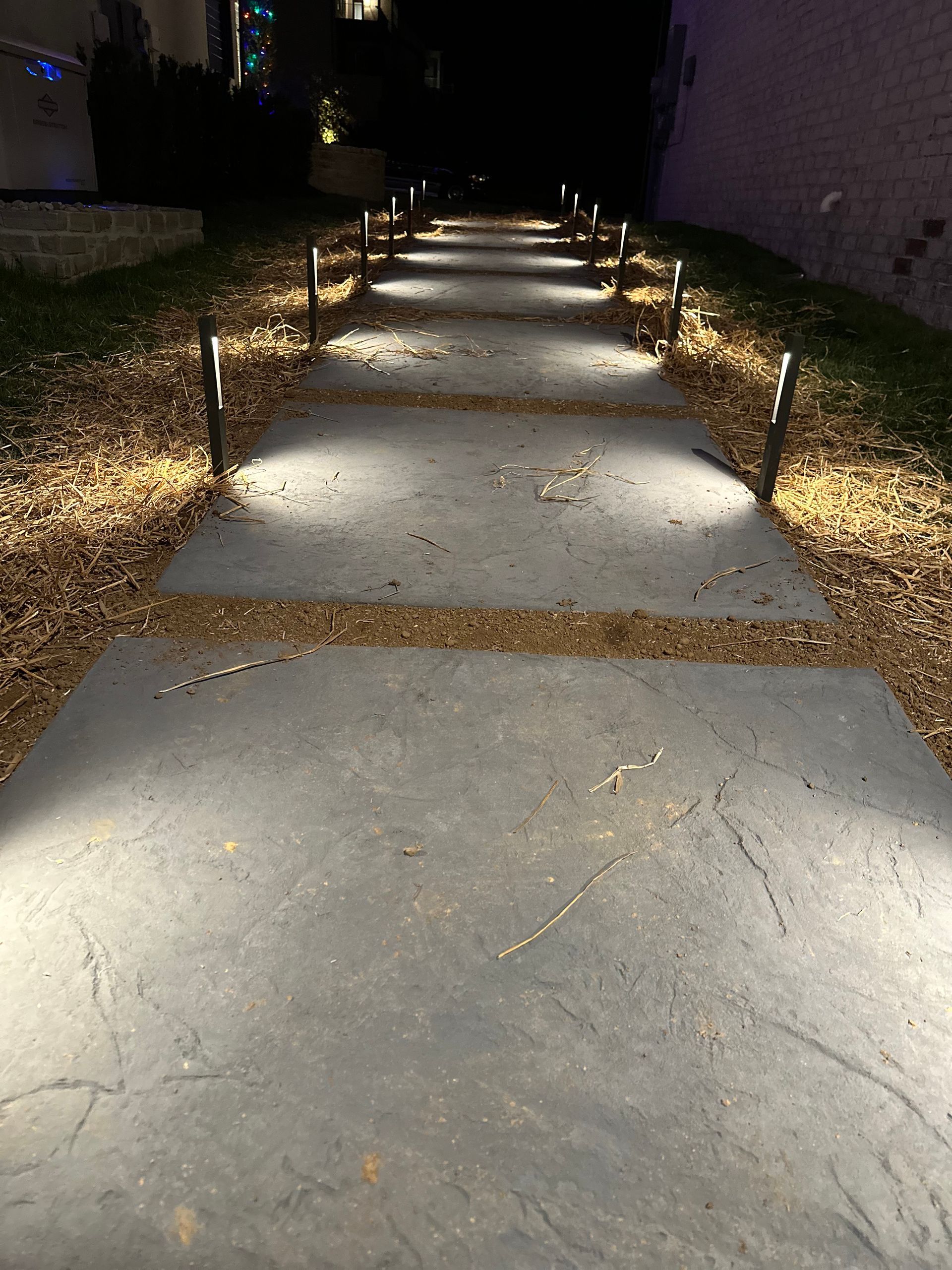 A concrete walkway with lights on it at night.