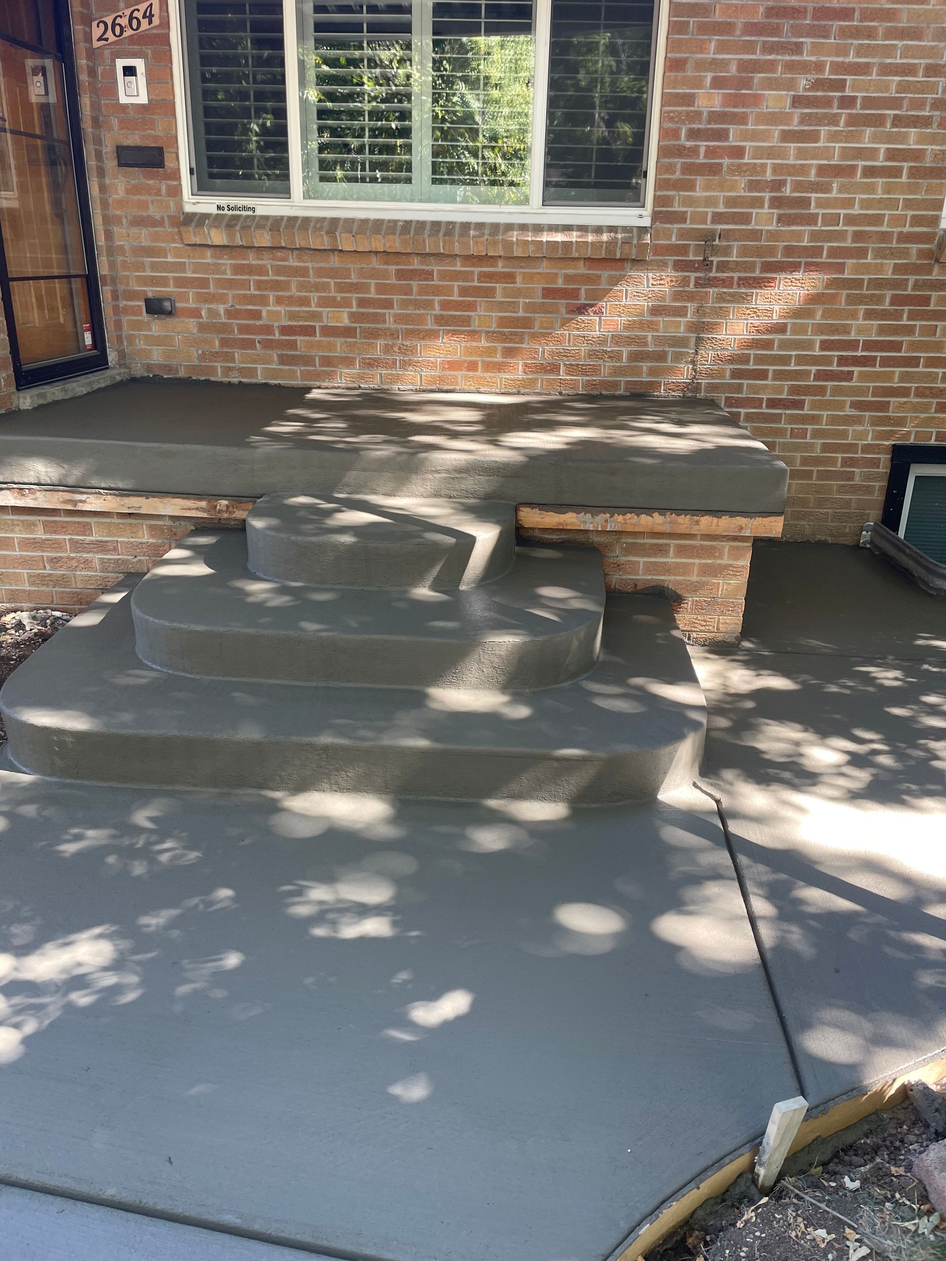 A brick house with concrete steps and a bench in front of it.