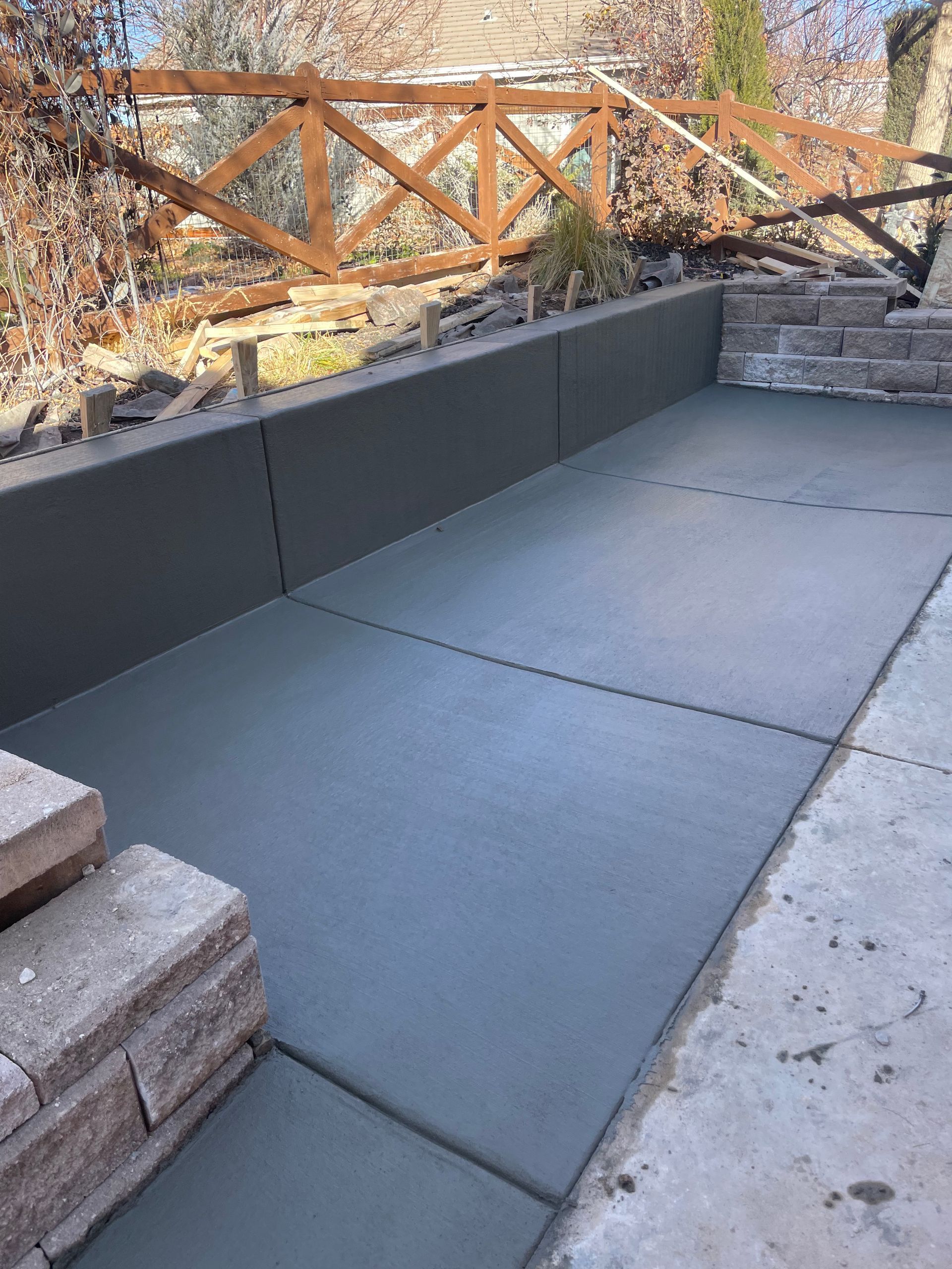 A concrete patio with a wooden fence in the background.