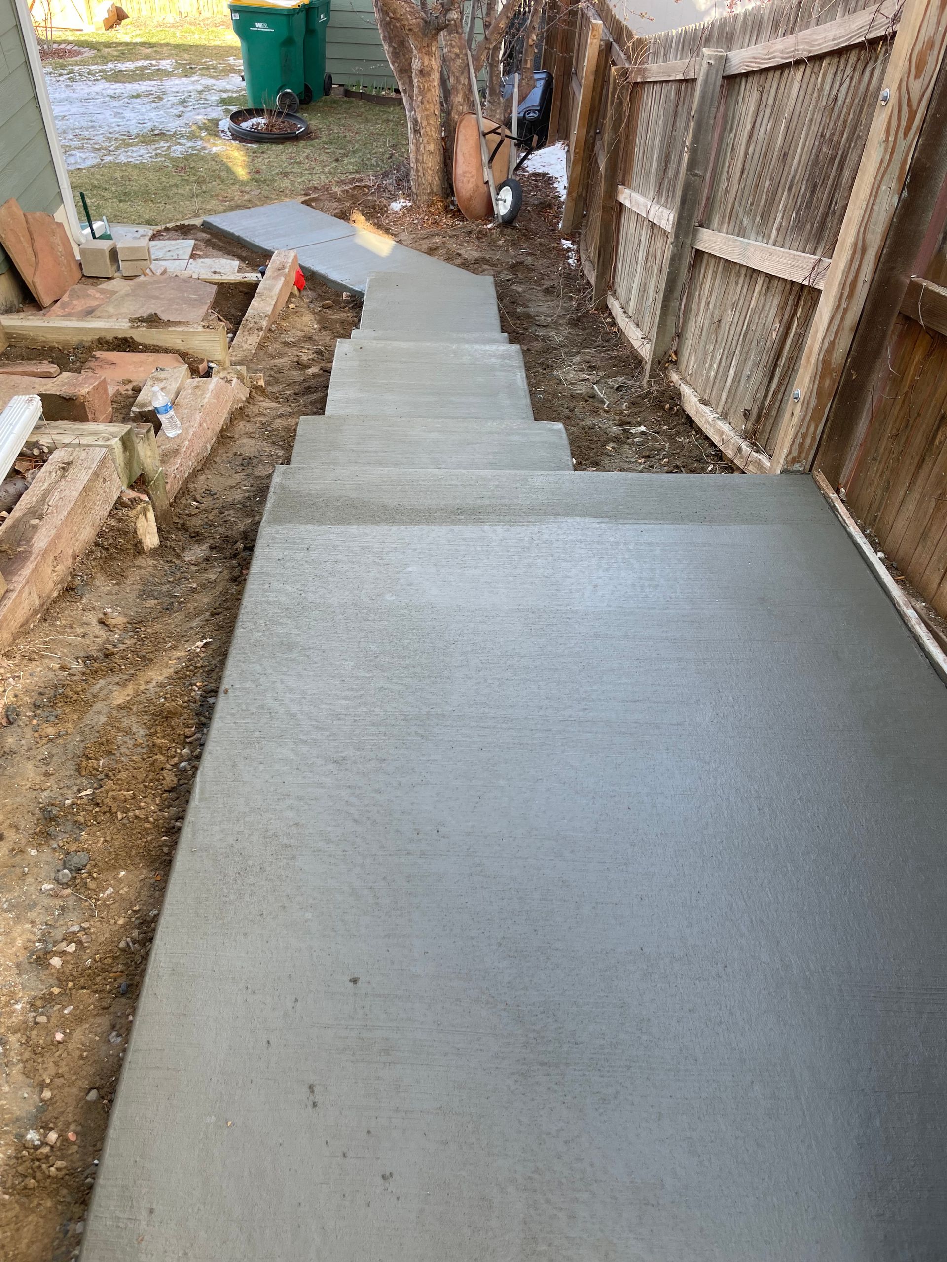 A set of concrete stairs leading up to a wooden fence.