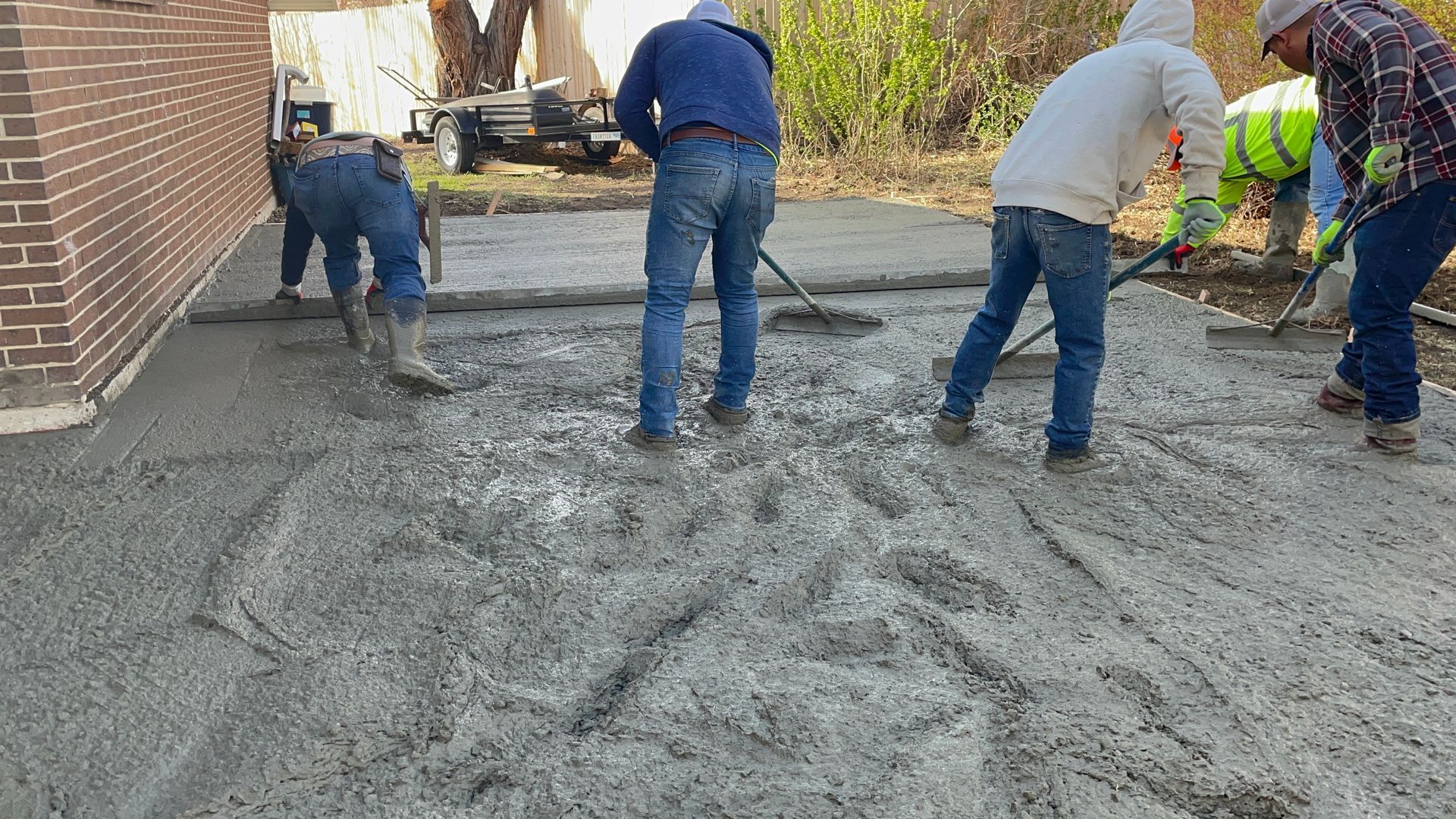 A group of men are working on a concrete driveway.