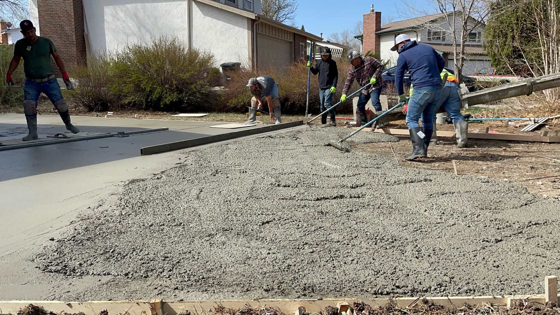 A group of construction workers are working on a concrete driveway.