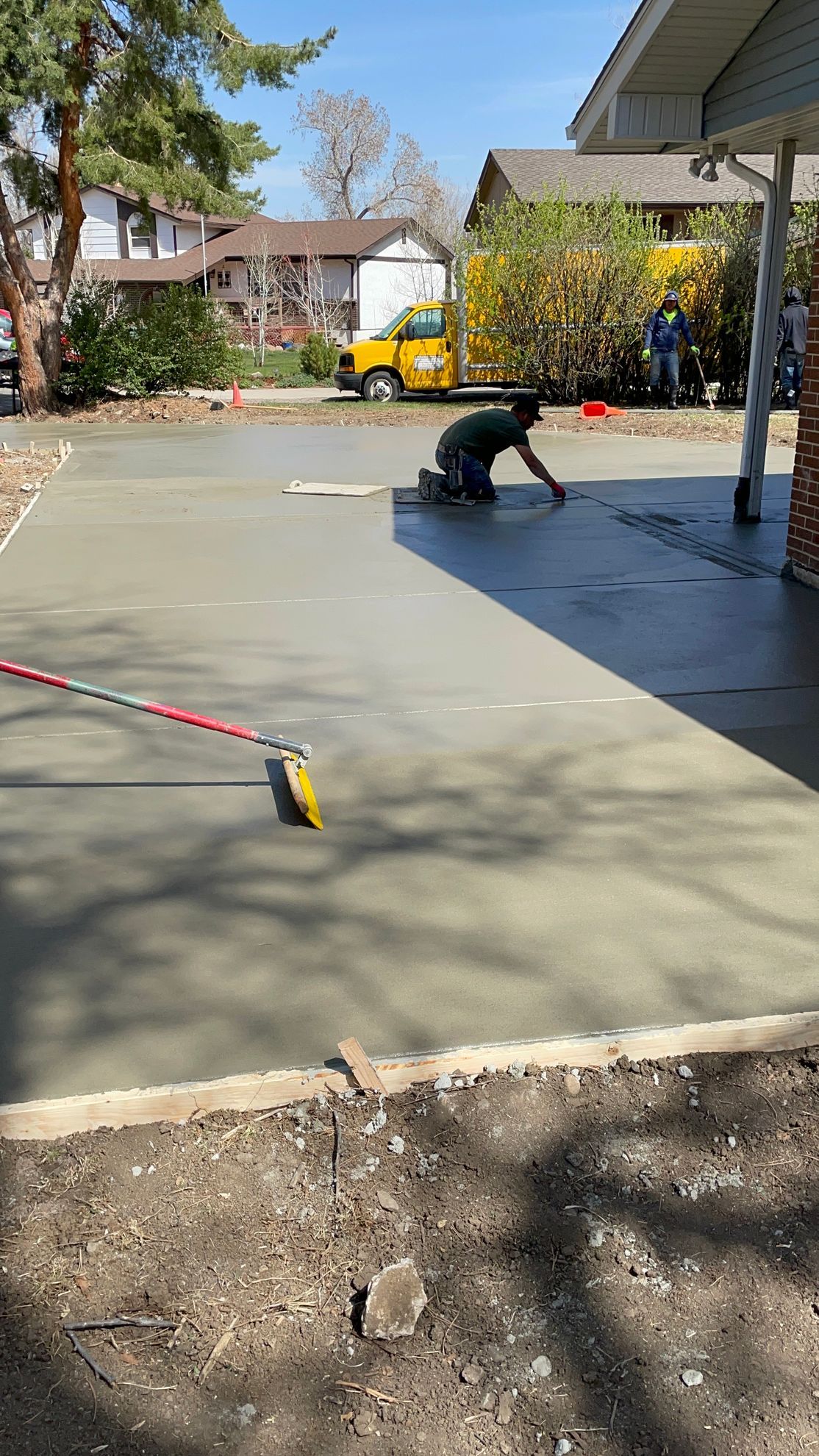 A man is working on a concrete driveway in front of a house.