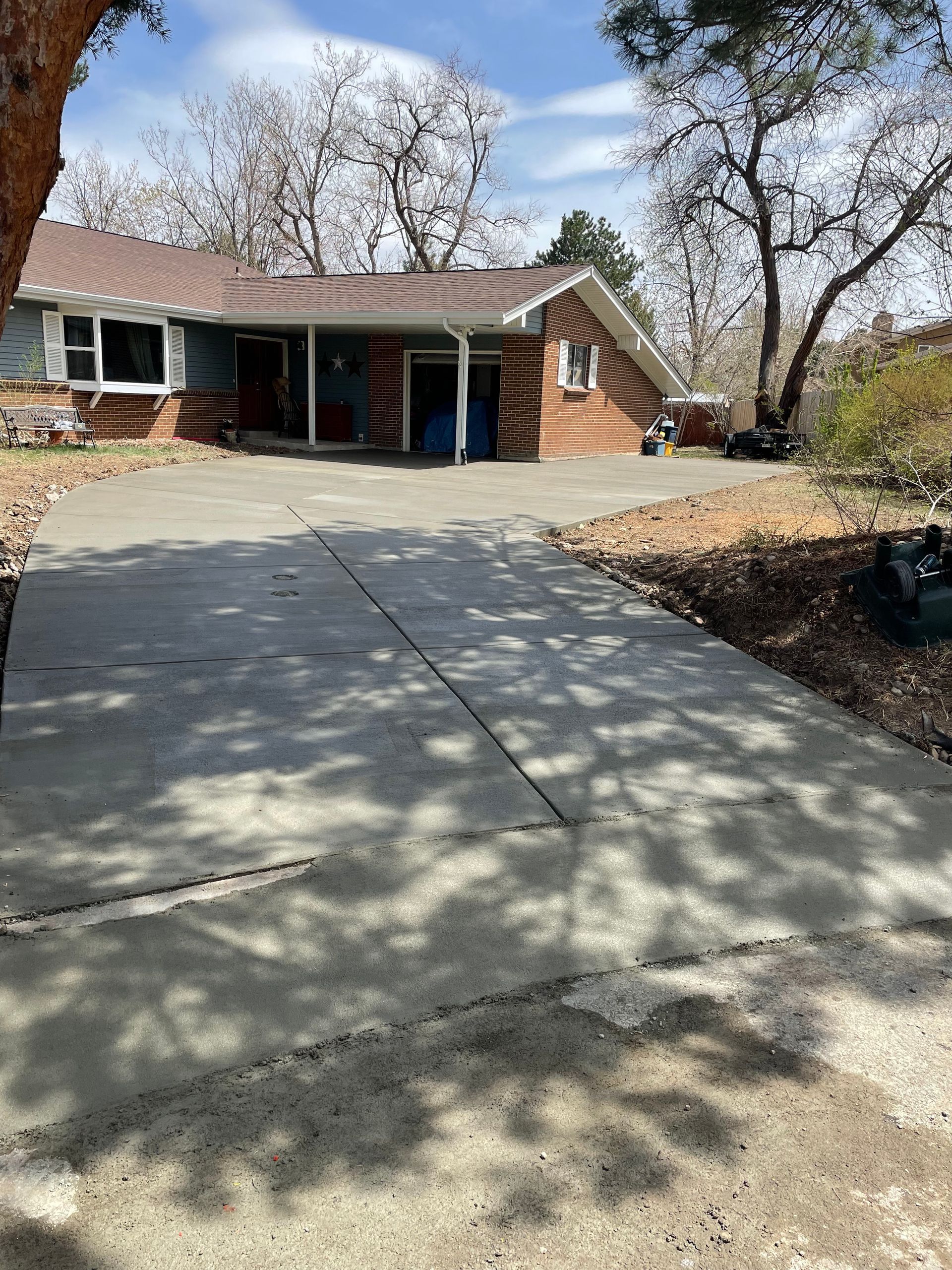 A brick house with a concrete driveway in front of it.