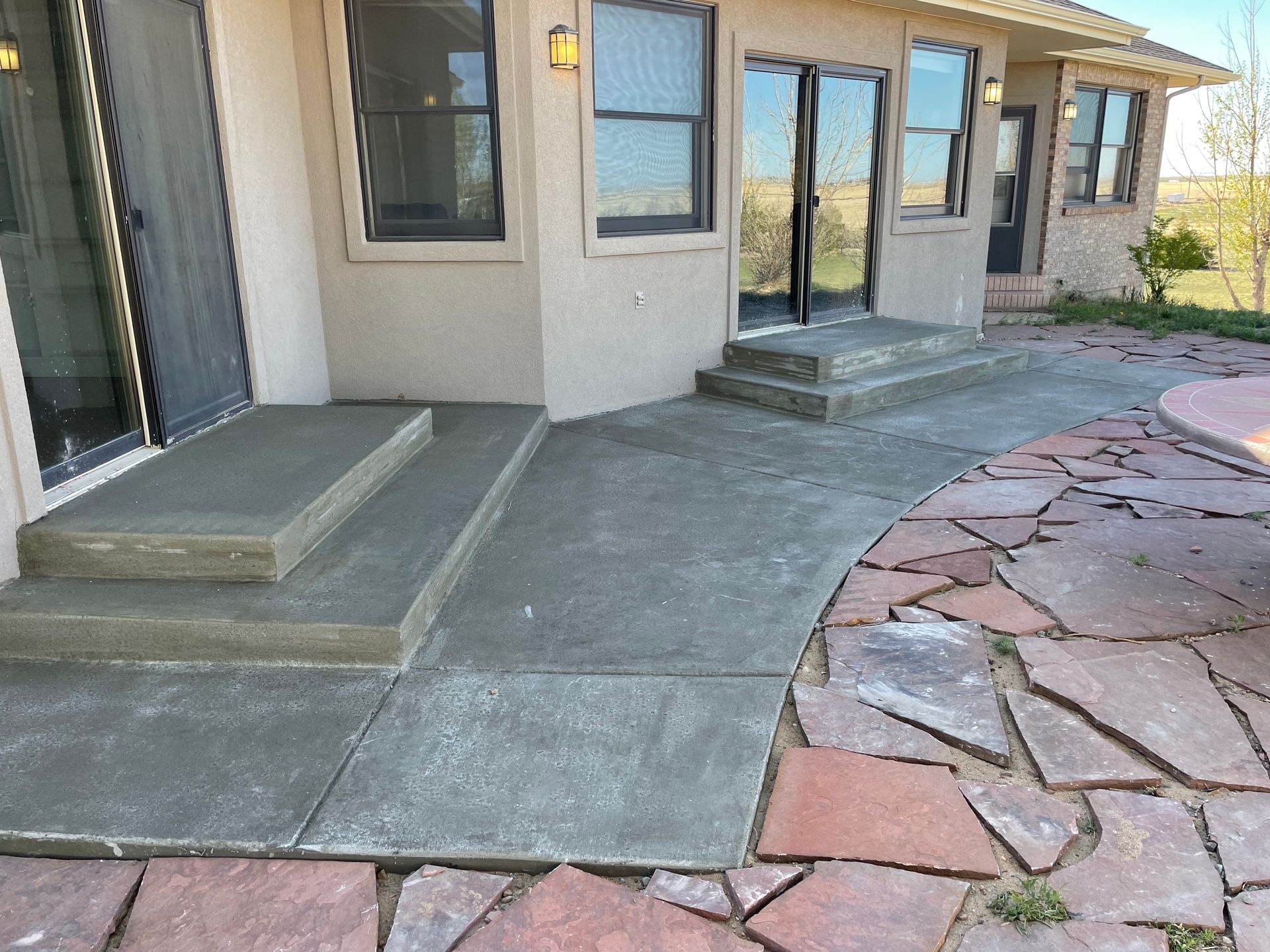 A concrete patio with steps and a stone walkway in front of a house.