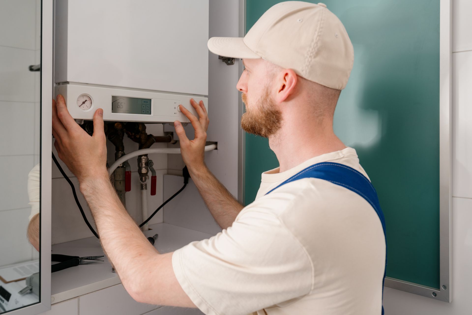Back rear view of a repairman is inspecting a gas boiler in a bathroom.