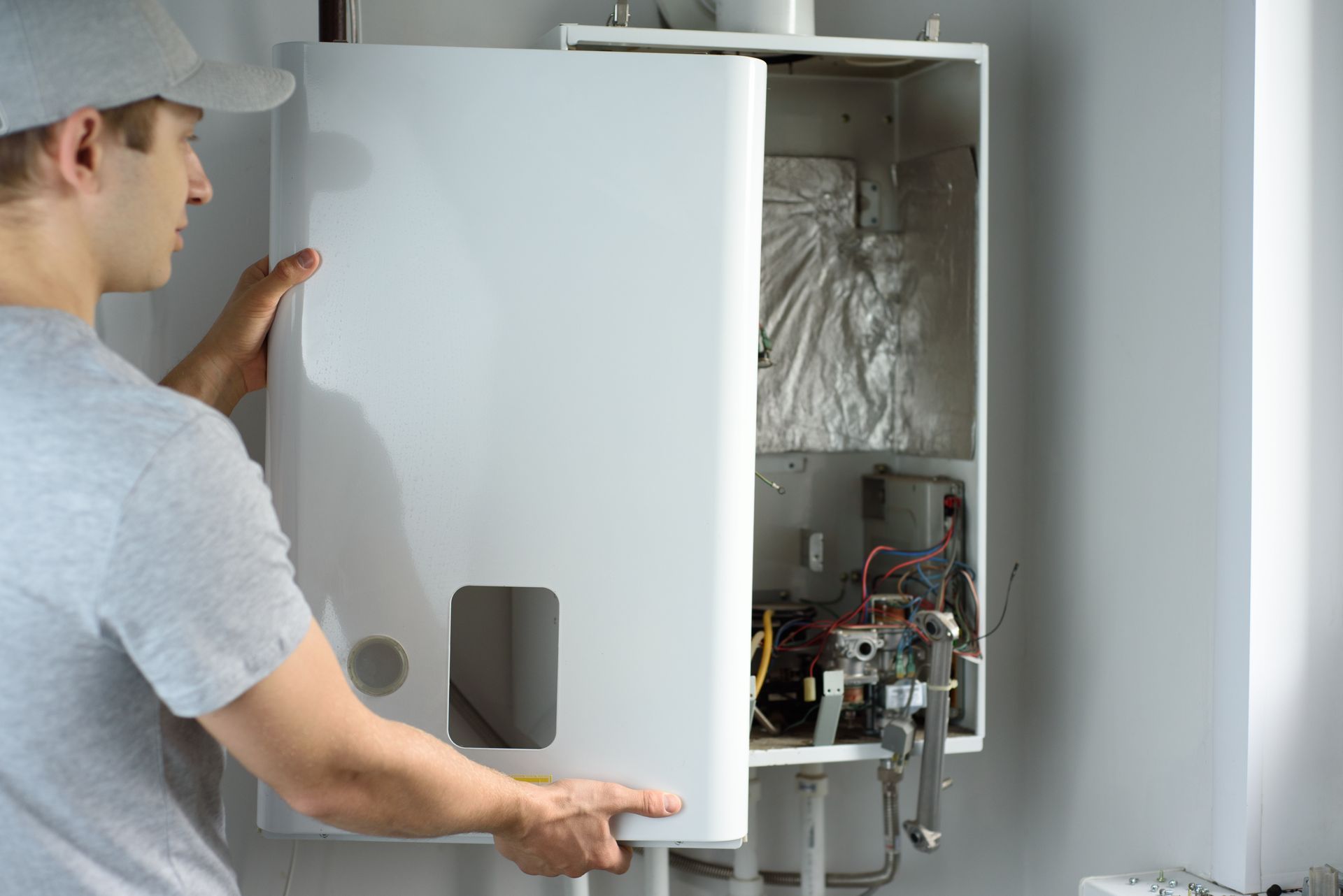 A man fixing a gas boiler within a home, highlighting essential heating system repair services.