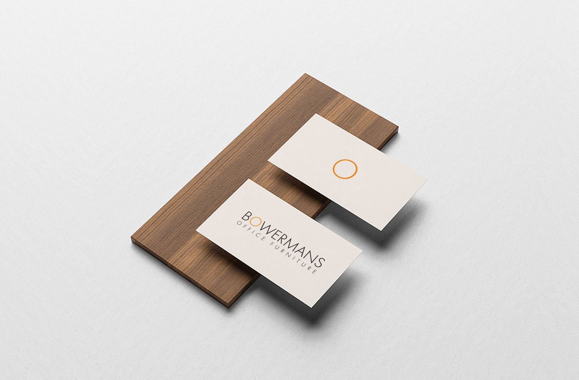 Three business cards are stacked on top of each other on a wooden surface.