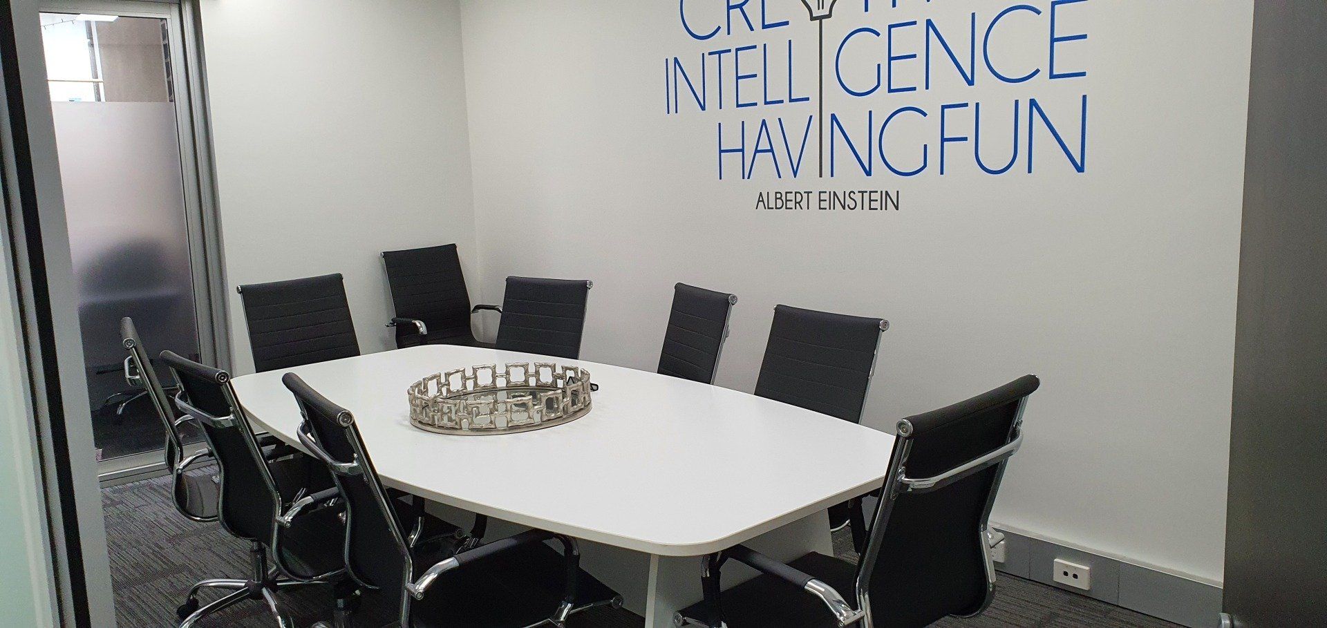A conference room with a white table and black chairs