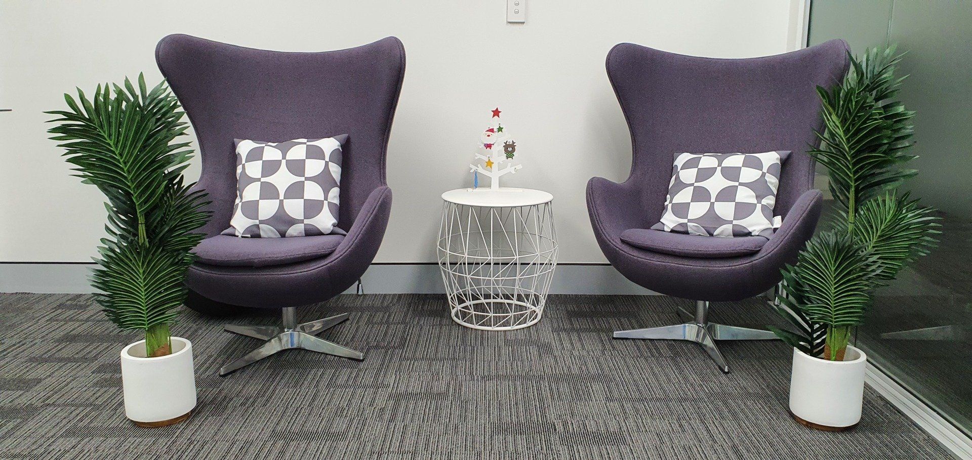 Two purple chairs and two potted plants in a room
