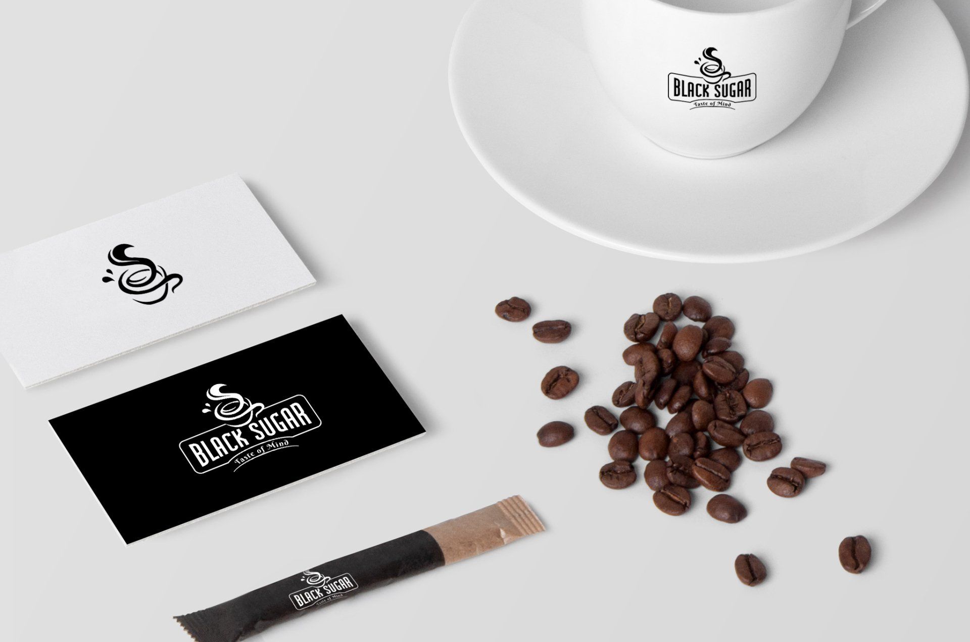 A cup of coffee on a saucer next to coffee beans and business cards