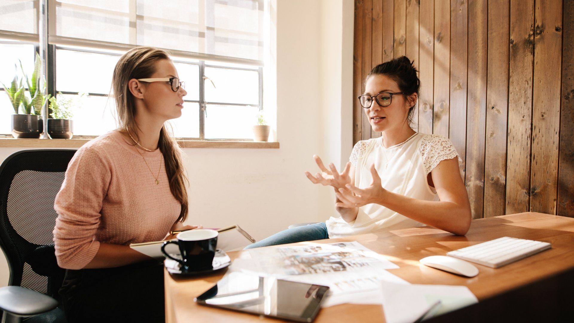 Two women are sitting at a table having a conversation.