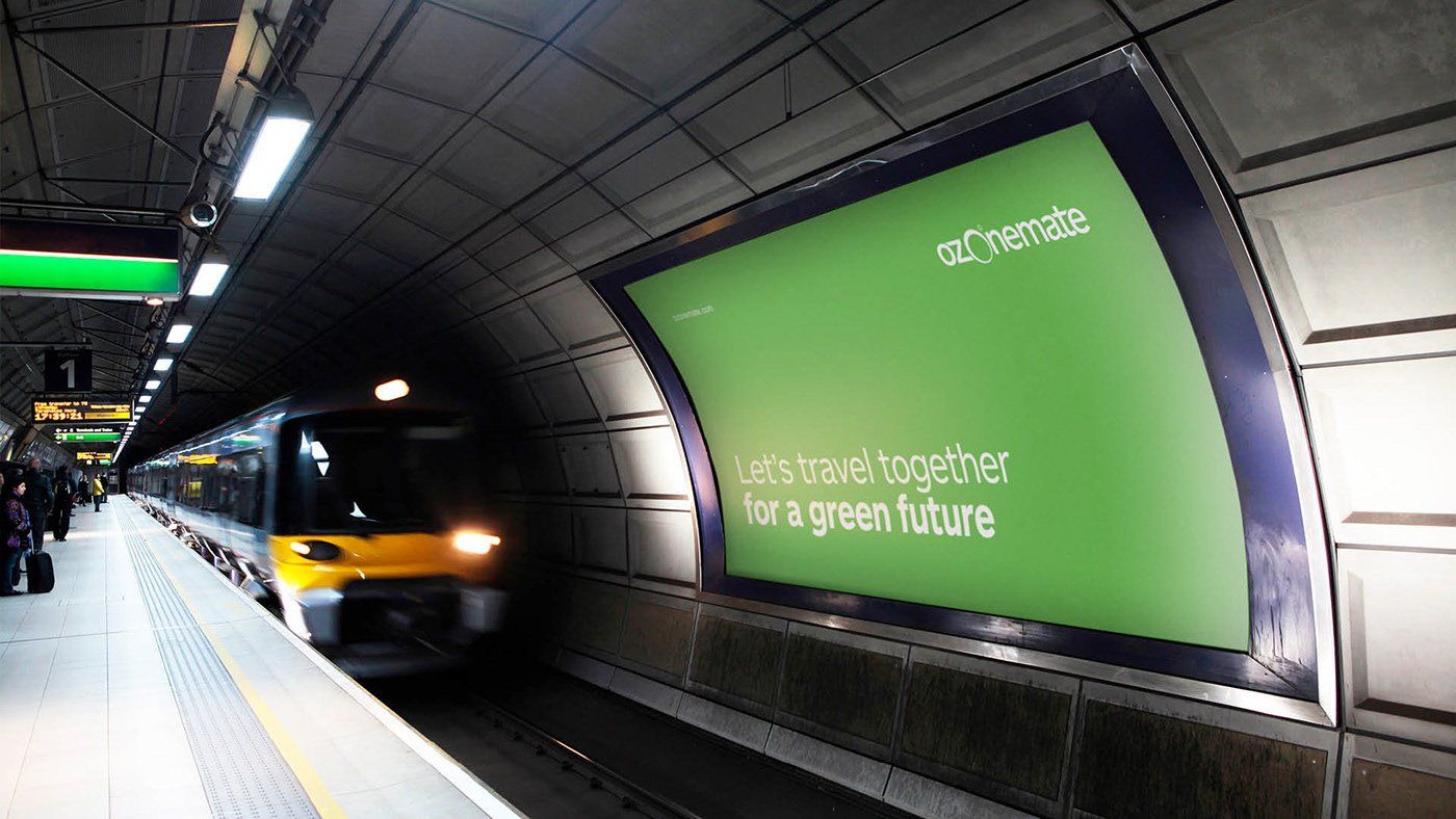 A train is pulling into a subway station with a green billboard advertising a green future