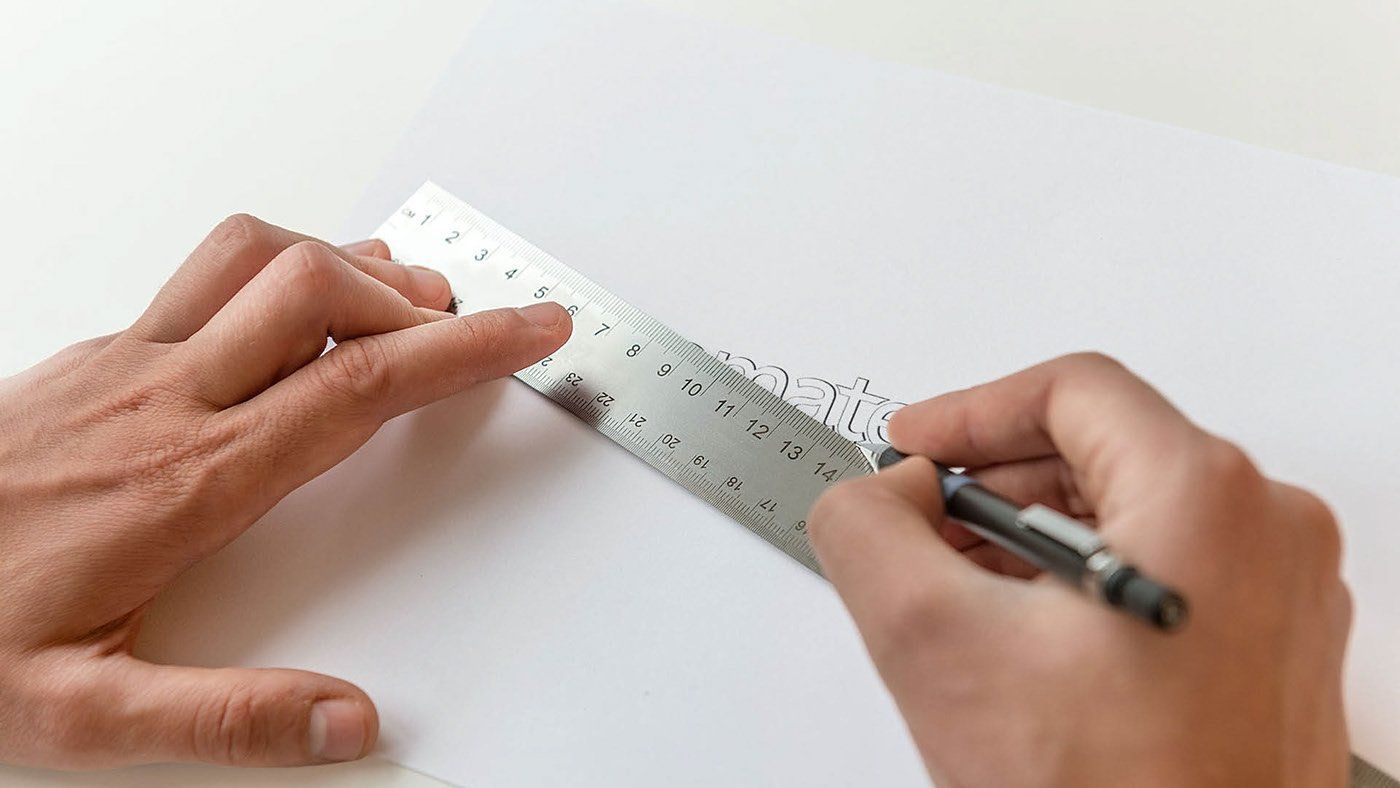A person is measuring something with a ruler and a pen.