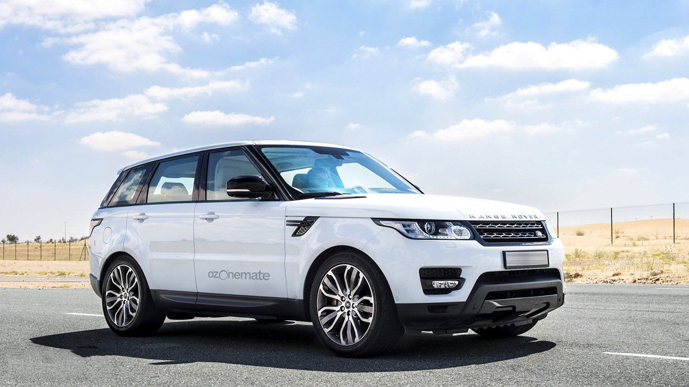 A white range rover sport is parked on the side of the road.
